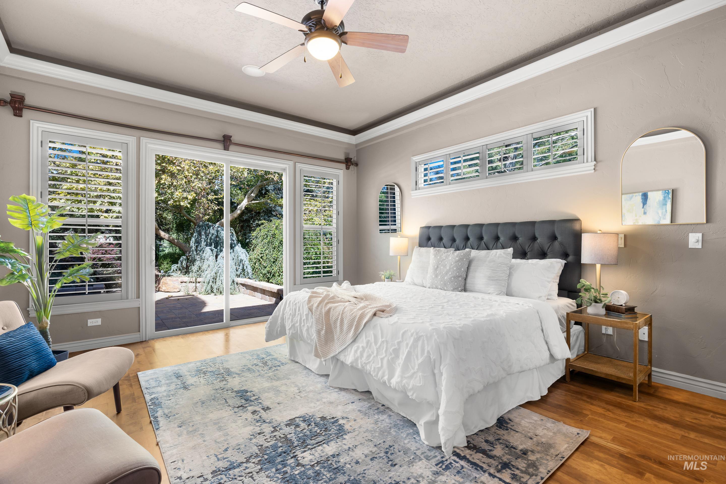 Bedroom with multiple windows, access to exterior, light wood finished floors, and ornamental molding