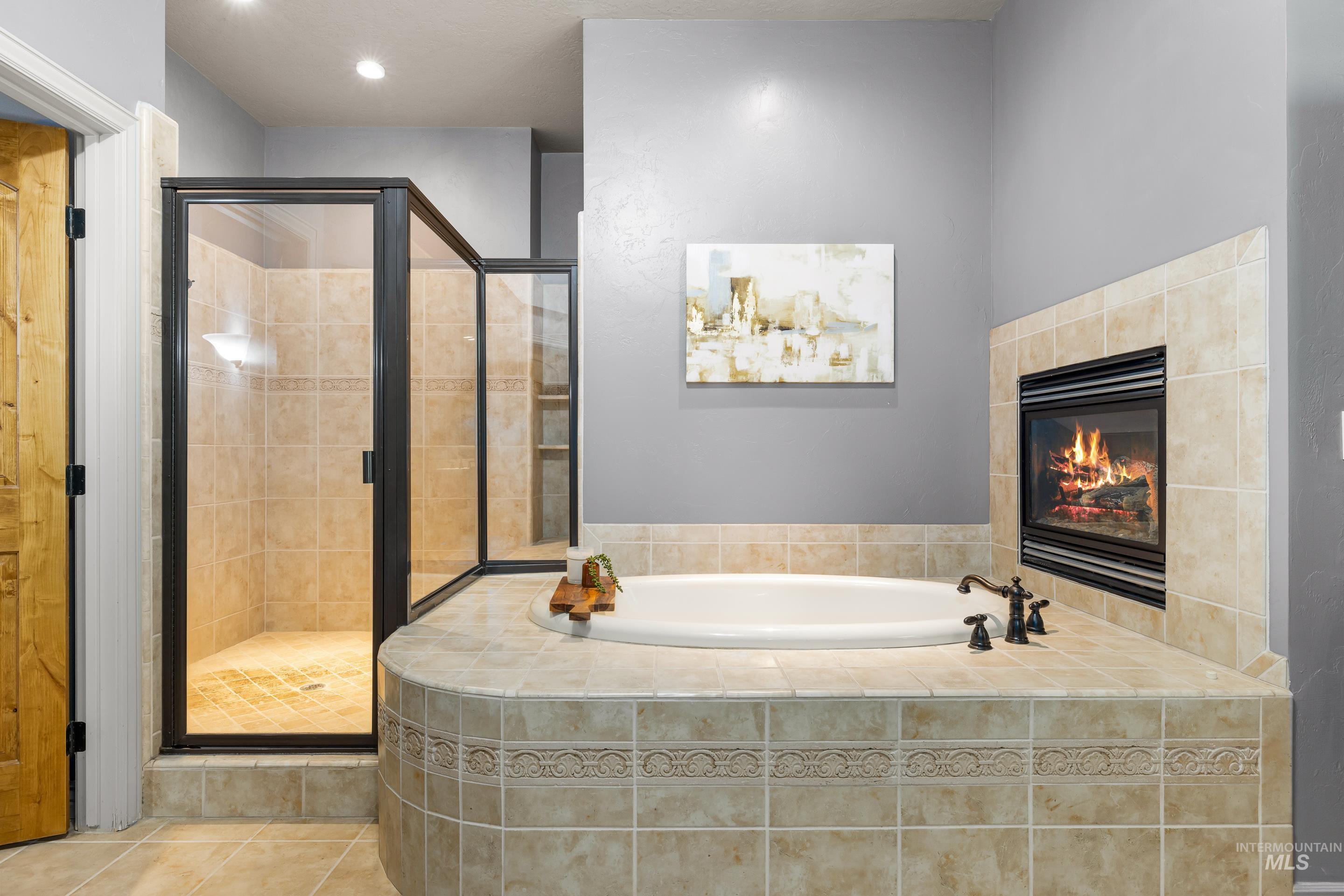 Bathroom with a garden tub, a stall shower, a tile fireplace, tile patterned floors, and recessed lighting