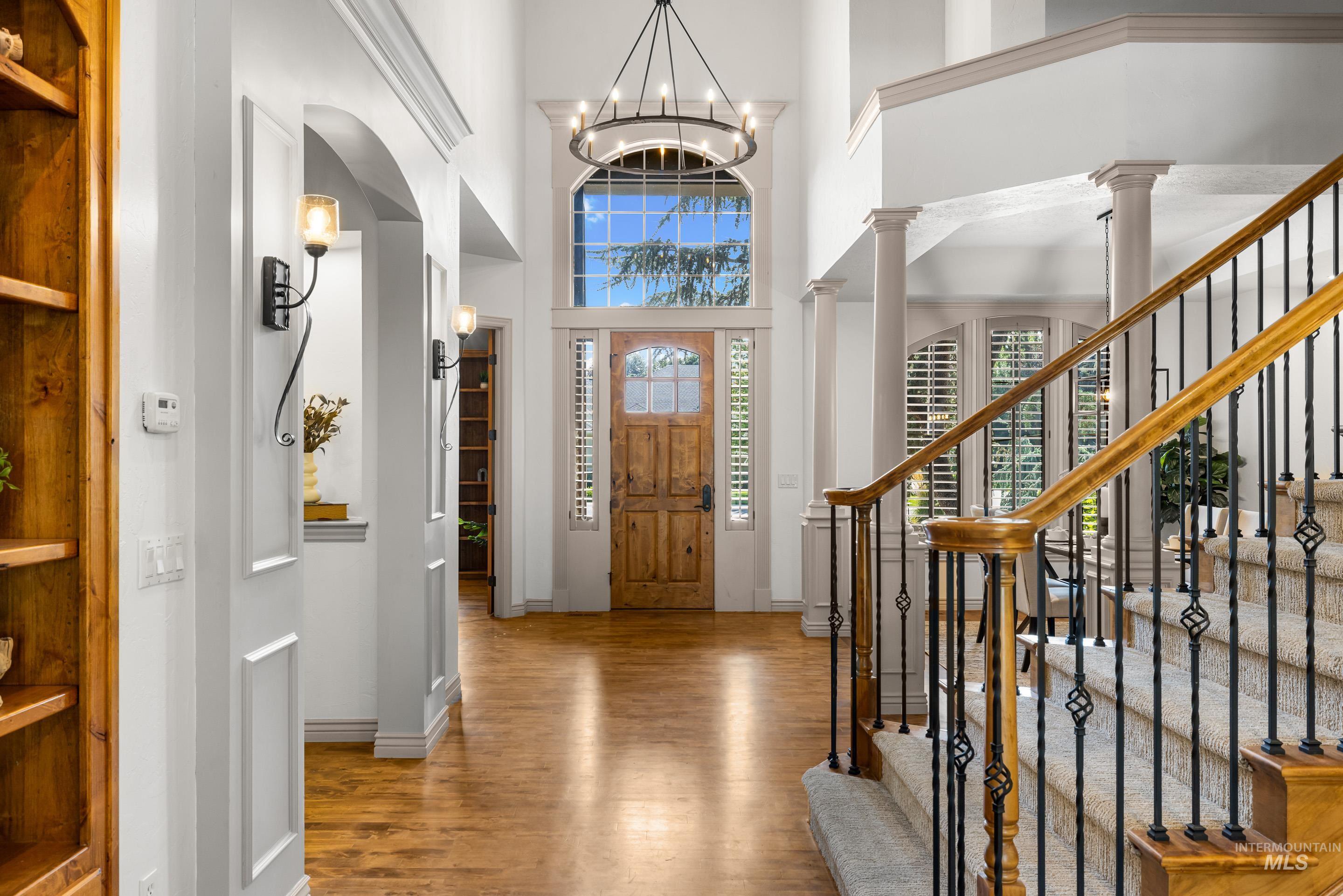 Foyer featuring wood finished floors, a high ceiling, plenty of natural light, a chandelier, and ornate columns