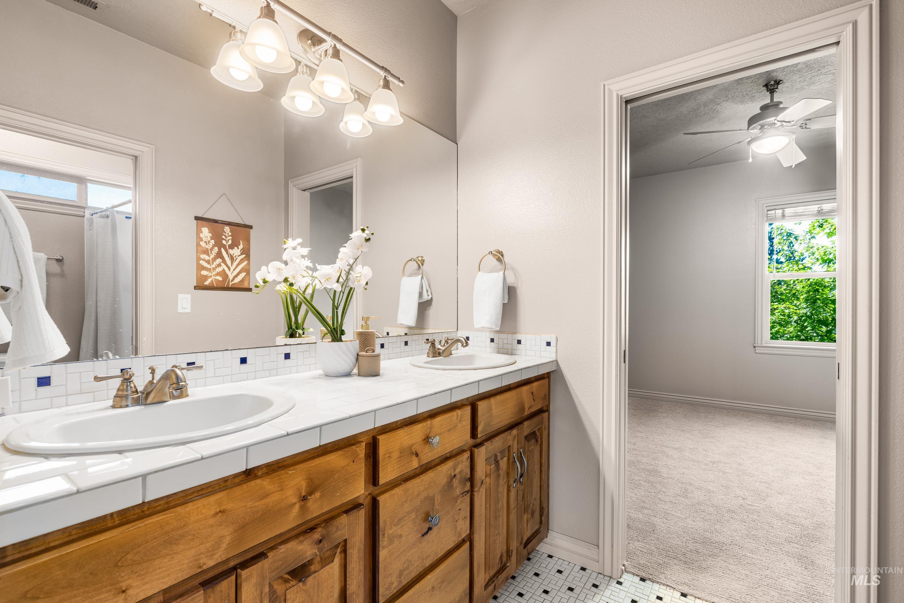 Bathroom featuring plenty of natural light, double vanity, tasteful backsplash, and light tile patterned floors