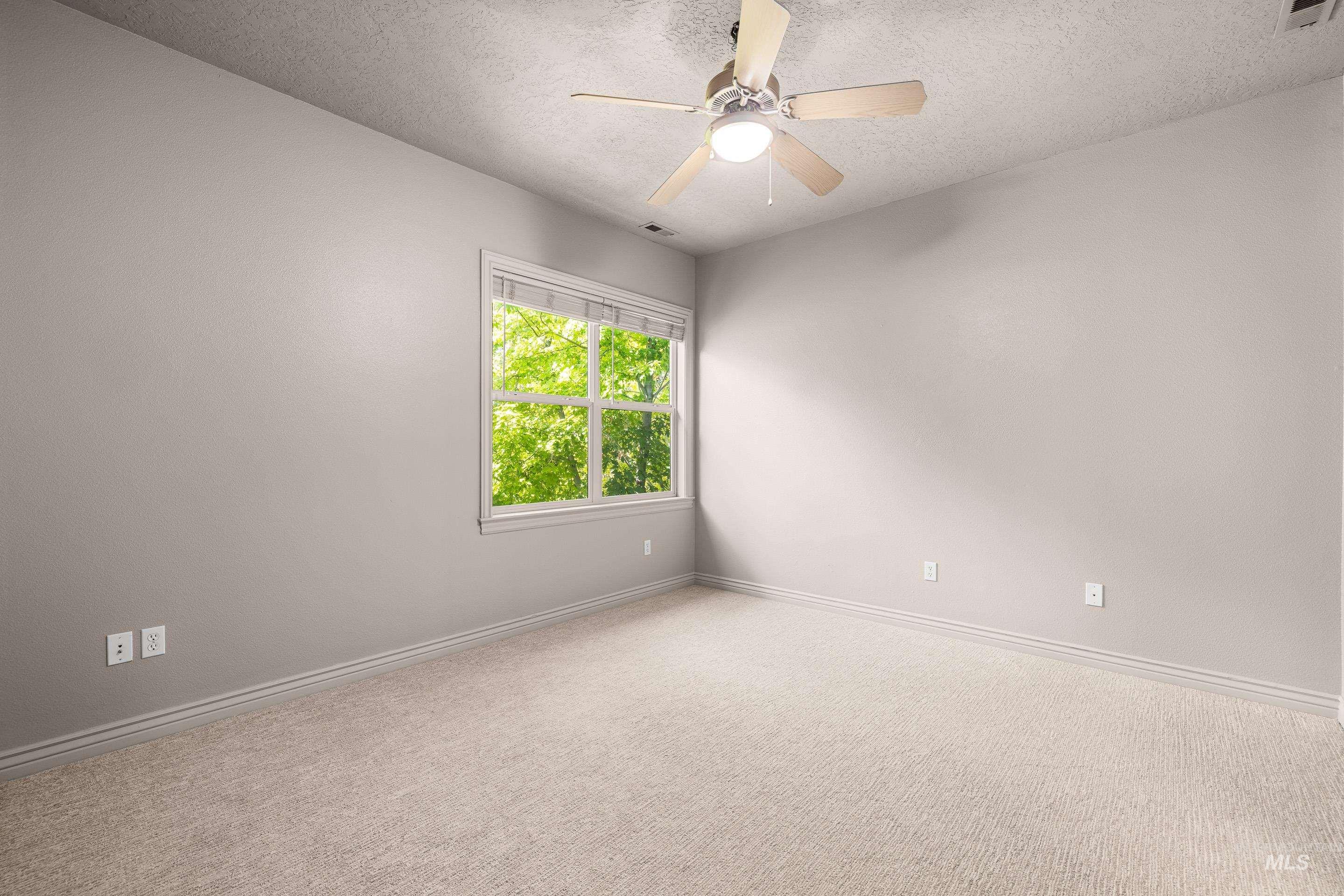 Carpeted empty room with a textured ceiling and a ceiling fan