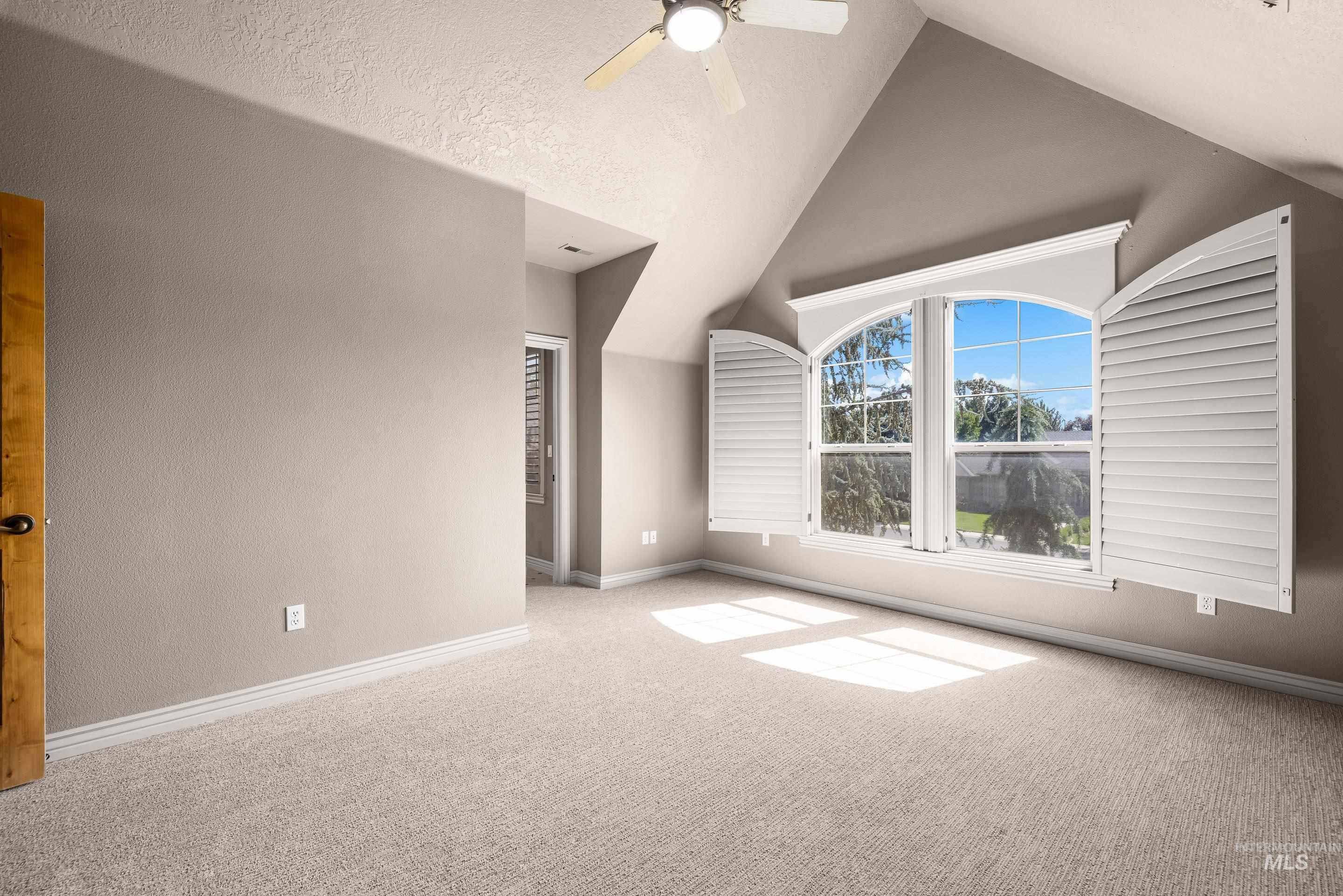 Additional living space featuring high vaulted ceiling, a textured wall, carpet flooring, and a ceiling fan