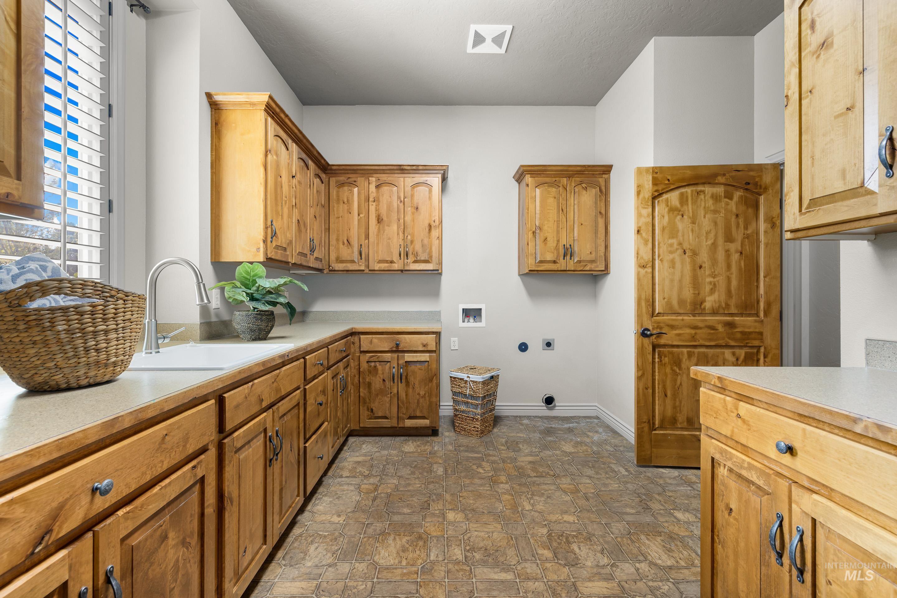 Washroom featuring stone finish flooring, washer hookup, cabinet space, and electric dryer hookup