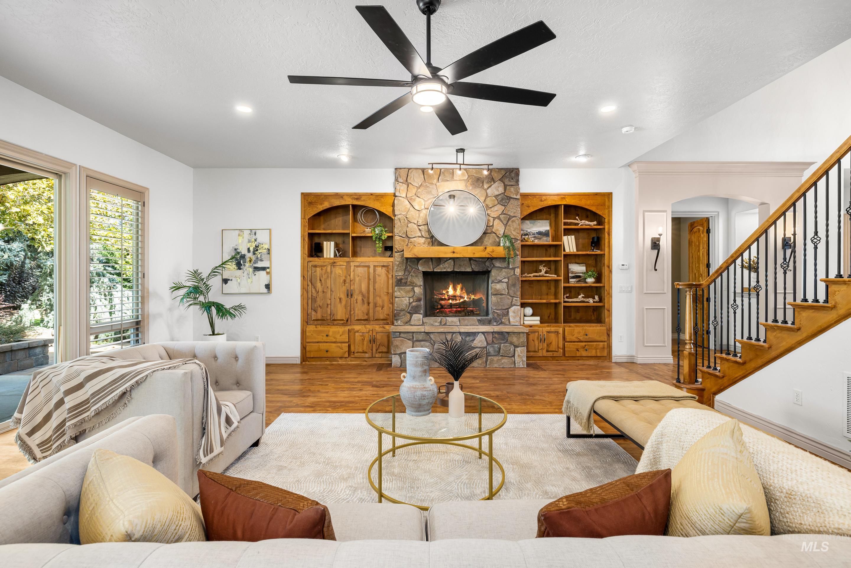 Living area with wood finished floors, a fireplace, built in shelves, stairs, and a textured ceiling