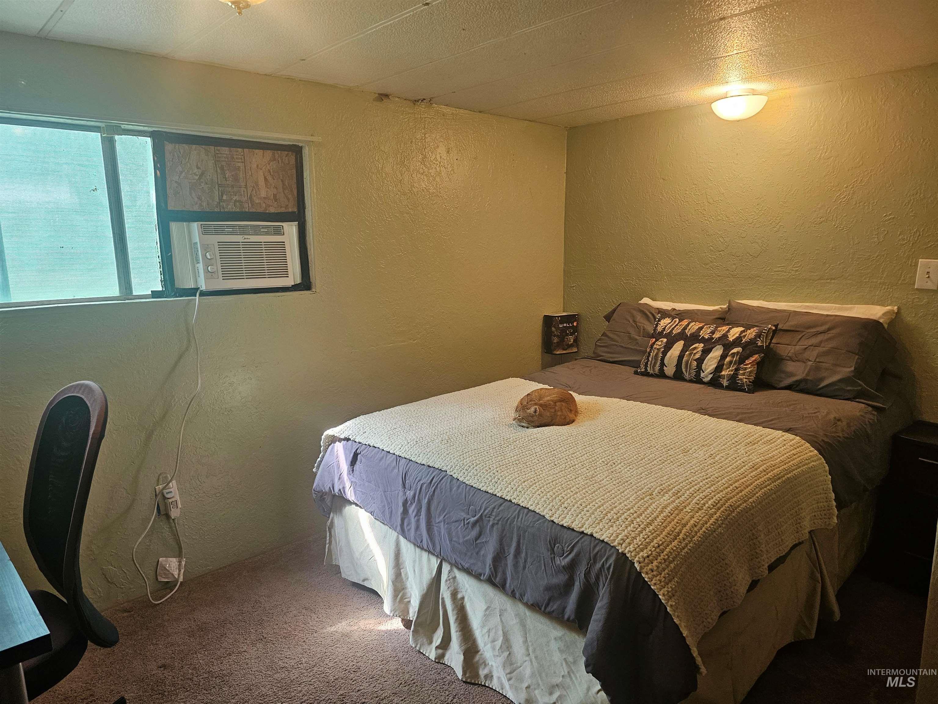 Carpeted bedroom with a textured wall and cooling unit