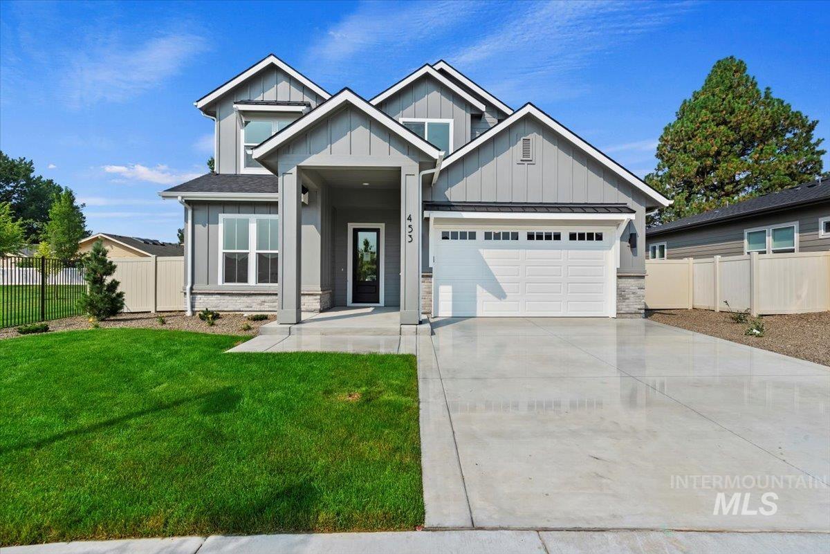 View of front of home featuring board and batten siding, concrete driveway, stone siding, an attached garage, and a metal roof