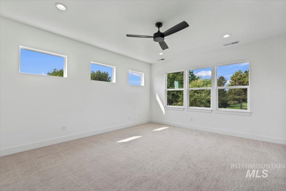 Unfurnished room with healthy amount of natural light, light colored carpet, recessed lighting, and ceiling fan