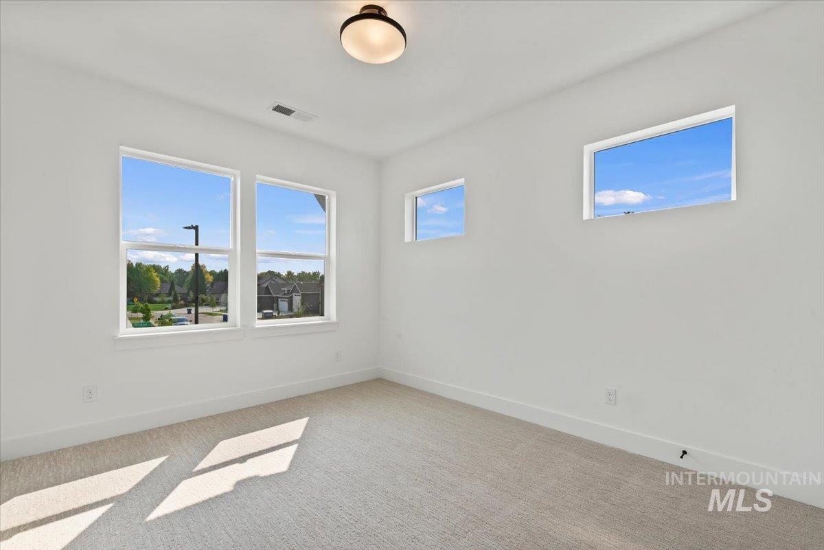 Spare room featuring light colored carpet and baseboards