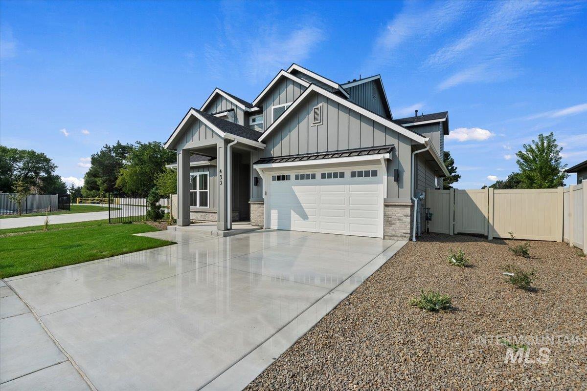 Craftsman inspired home with a standing seam roof, a metal roof, driveway, a gate, and board and batten siding