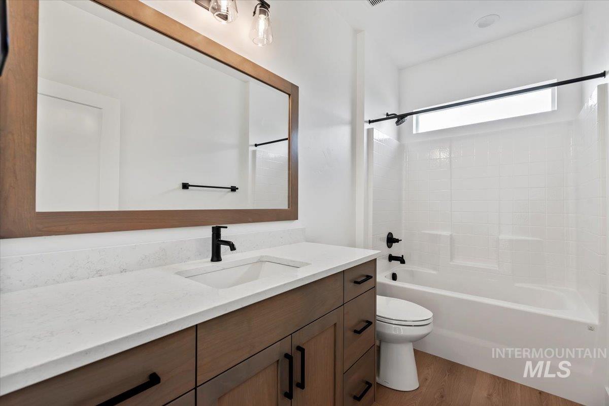Full bath with shower / bathtub combination, vanity, and light wood-type flooring