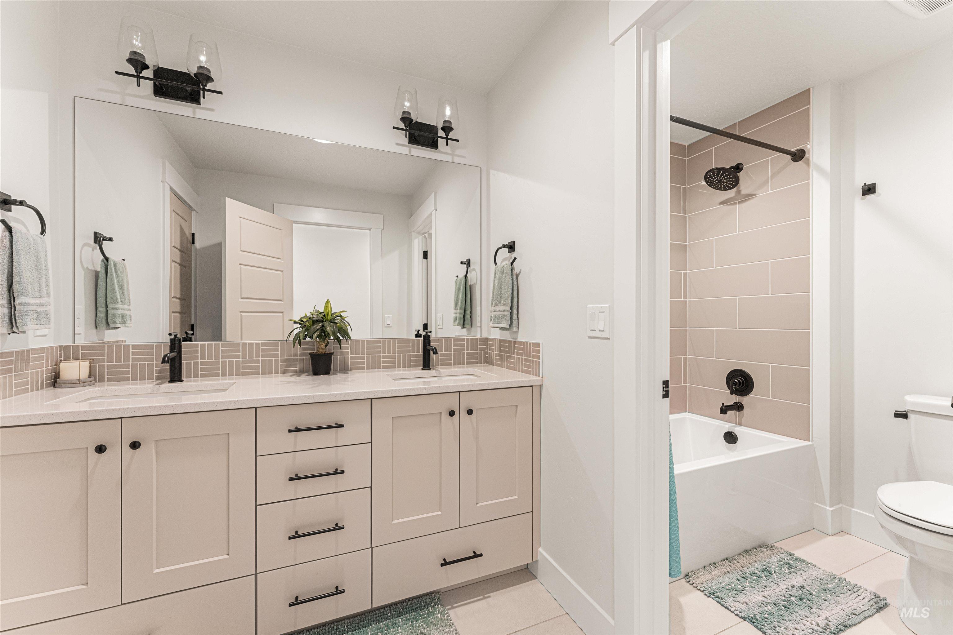 Upstairs full bath with double vanity, tiled tub / shower combination.