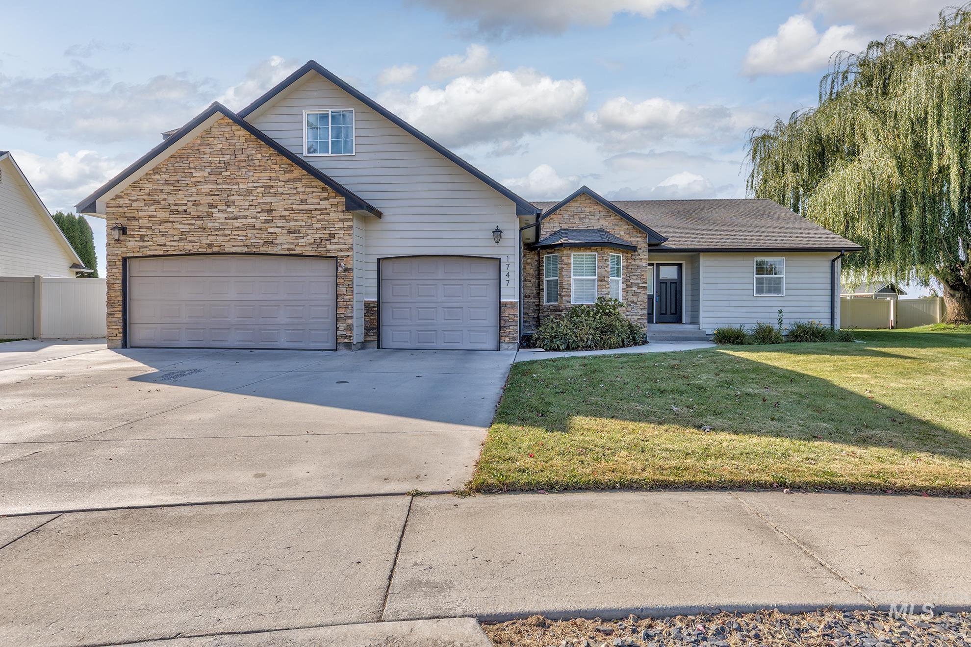 View of front of home with driveway, a garage, and stone siding