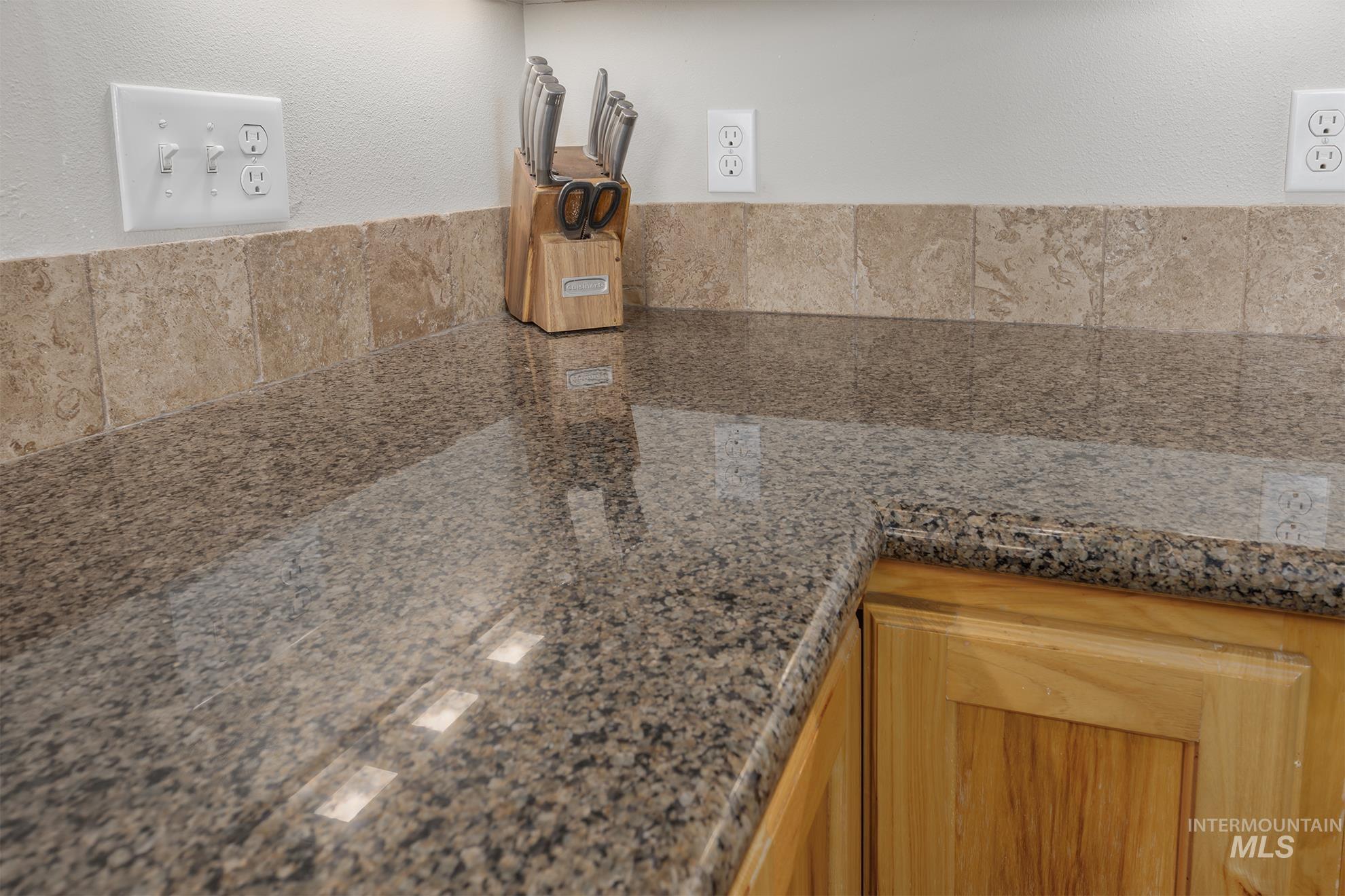 Kitchen view of dark stone counters and a textured wall