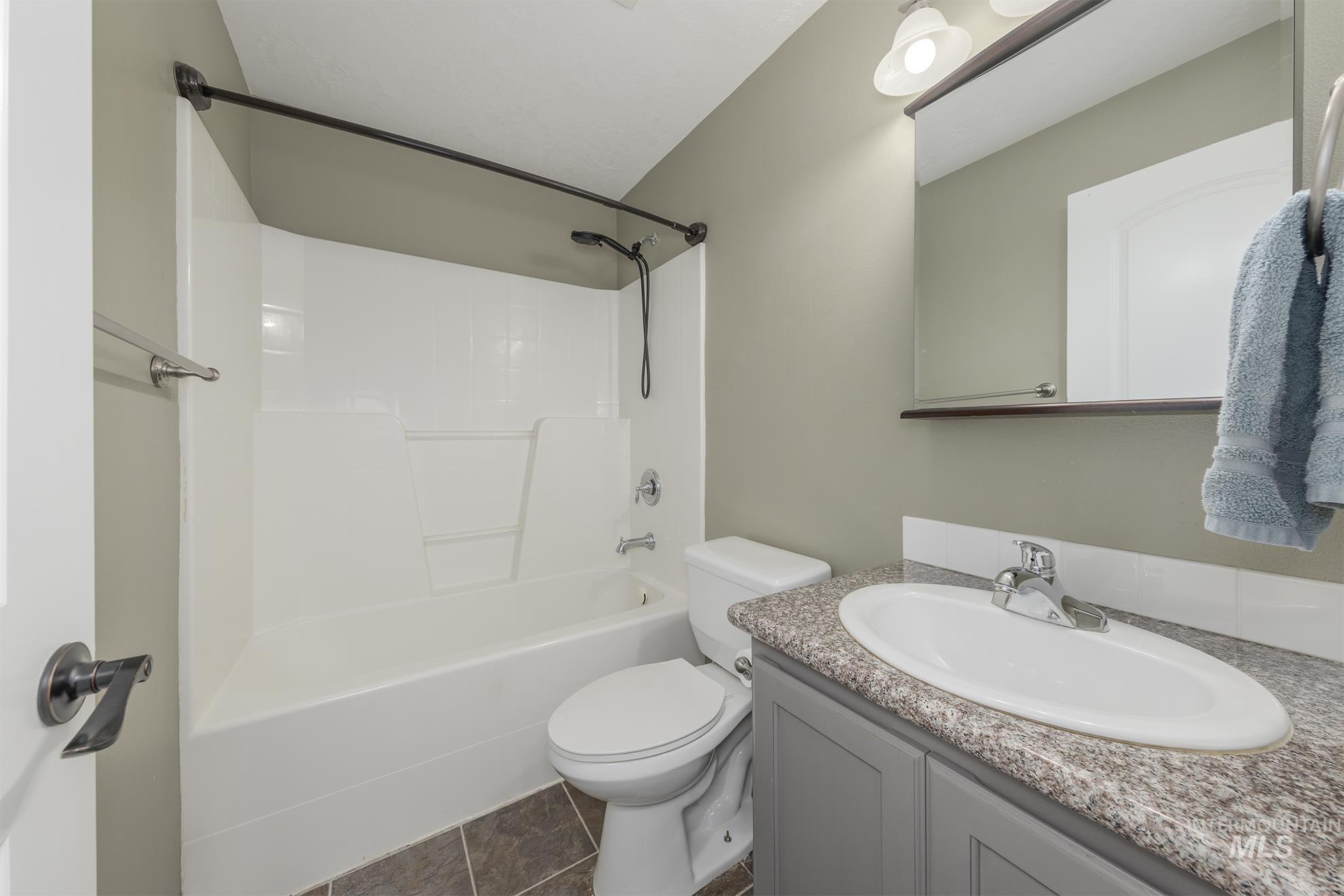 Full bath with vanity, tub / shower combination, and dark tile patterned flooring