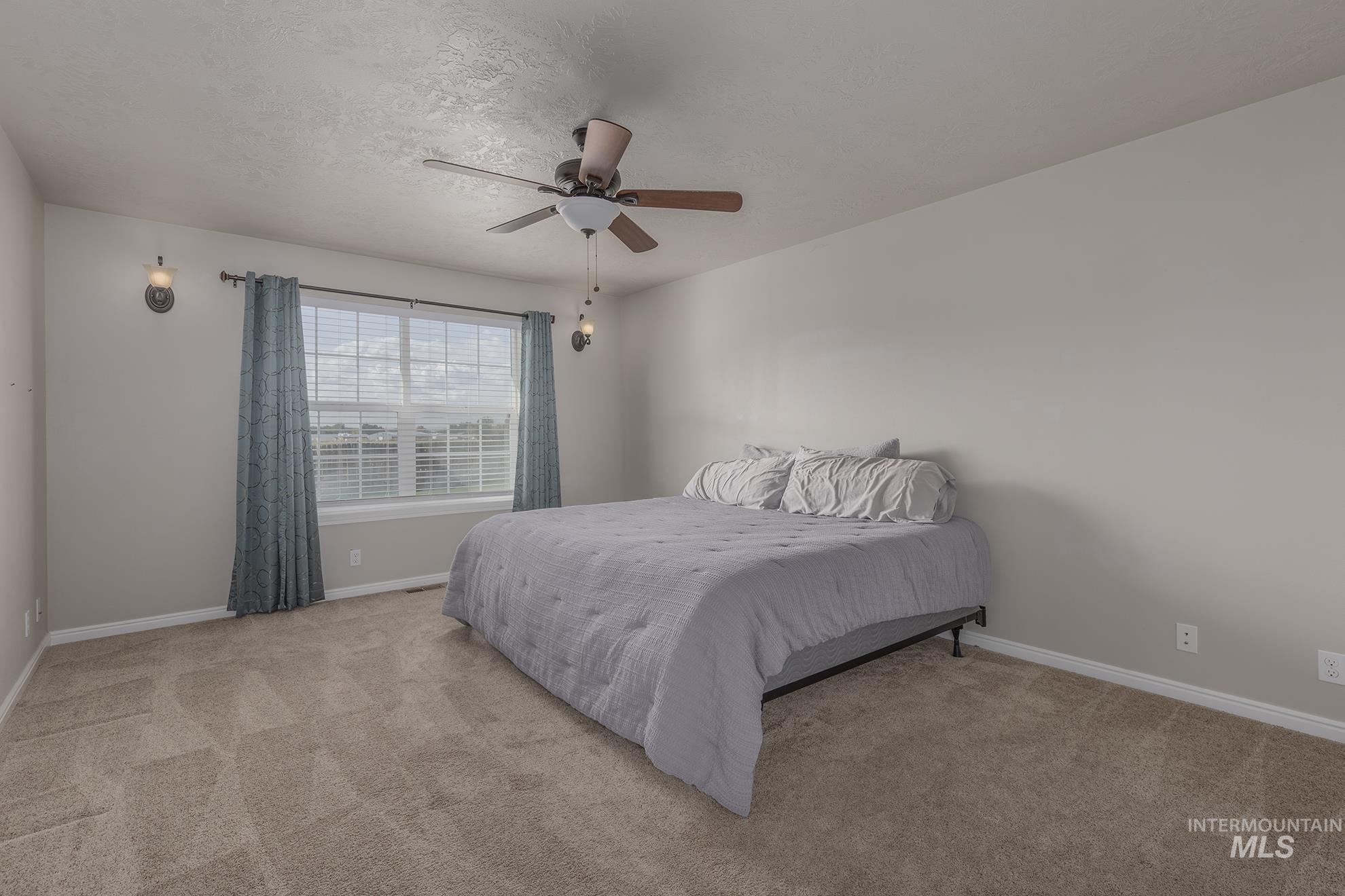 Bedroom with carpet floors, a textured ceiling, and a ceiling fan