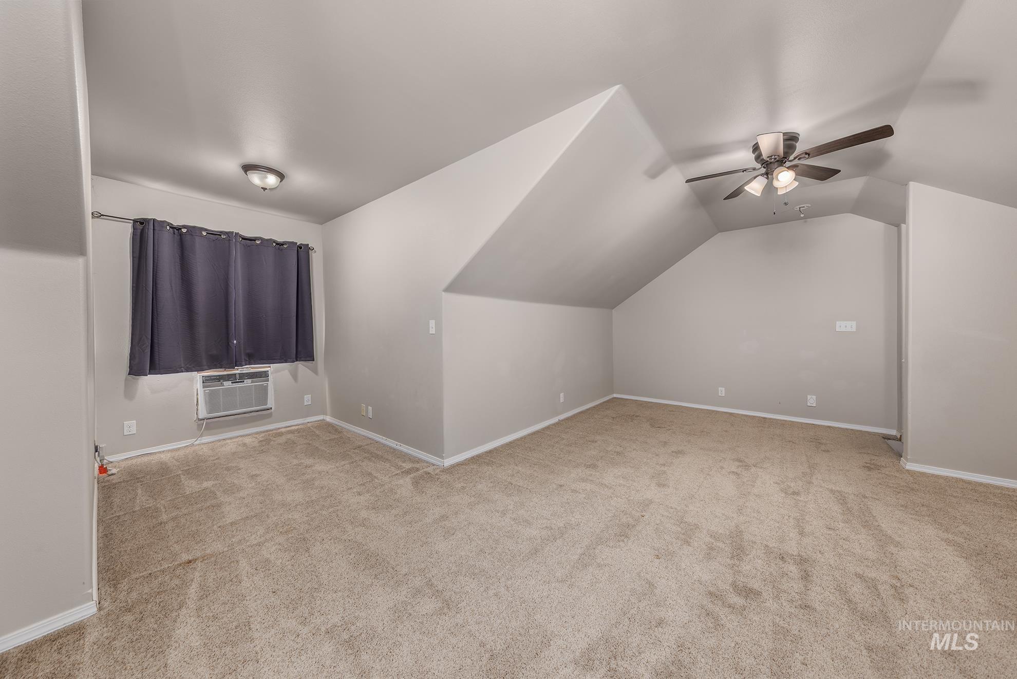 Bonus room featuring light colored carpet, lofted ceiling, and ceiling fan upstairs