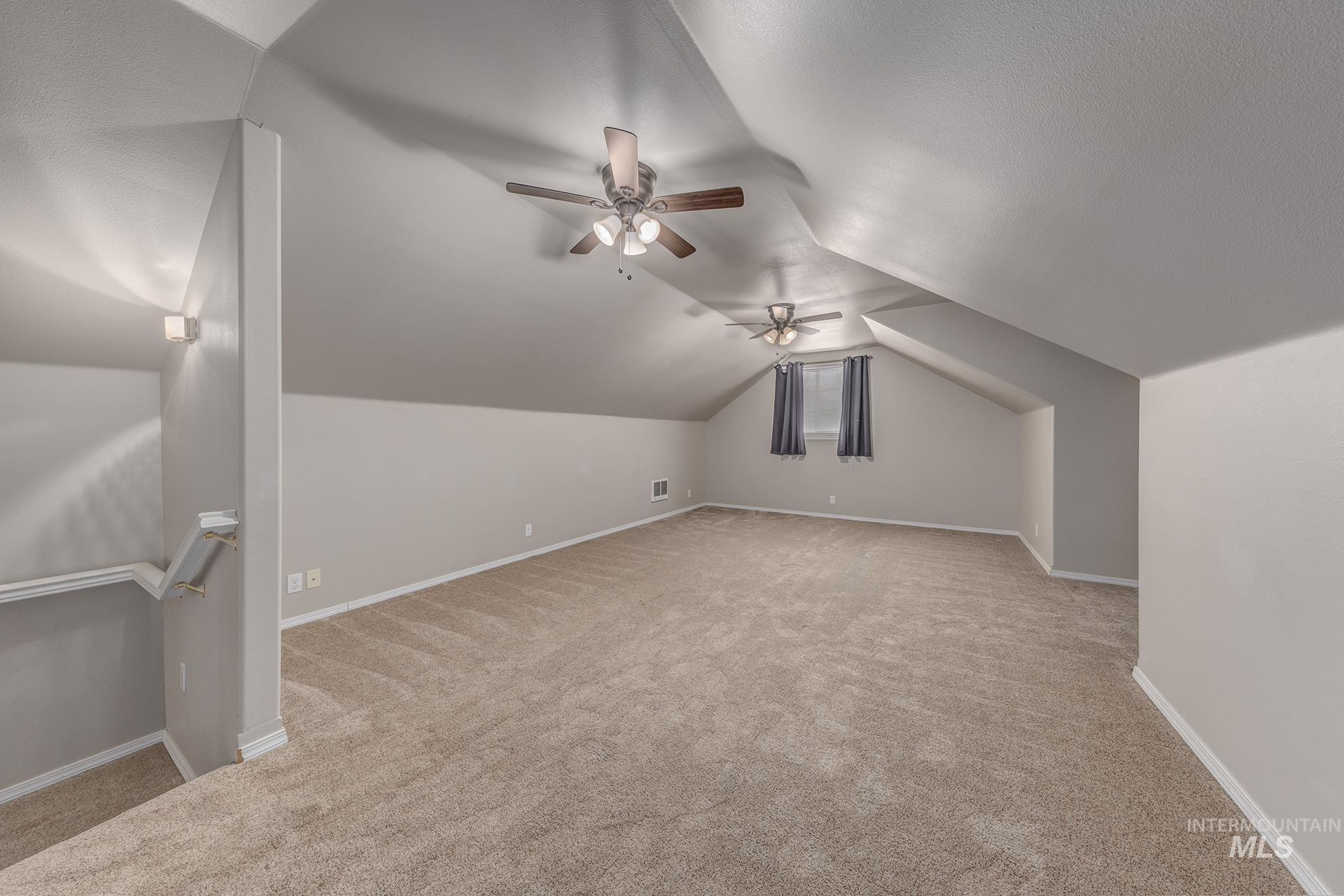 Bonus room featuring vaulted ceiling, light carpet, a ceiling fan, and a textured ceiling