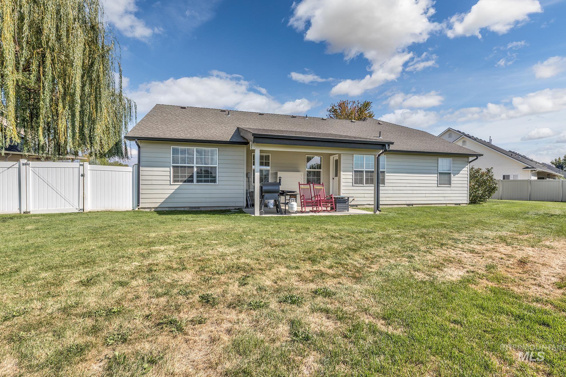 Rear view of property with a gate, a patio, roof with shingles, and a fenced backyard