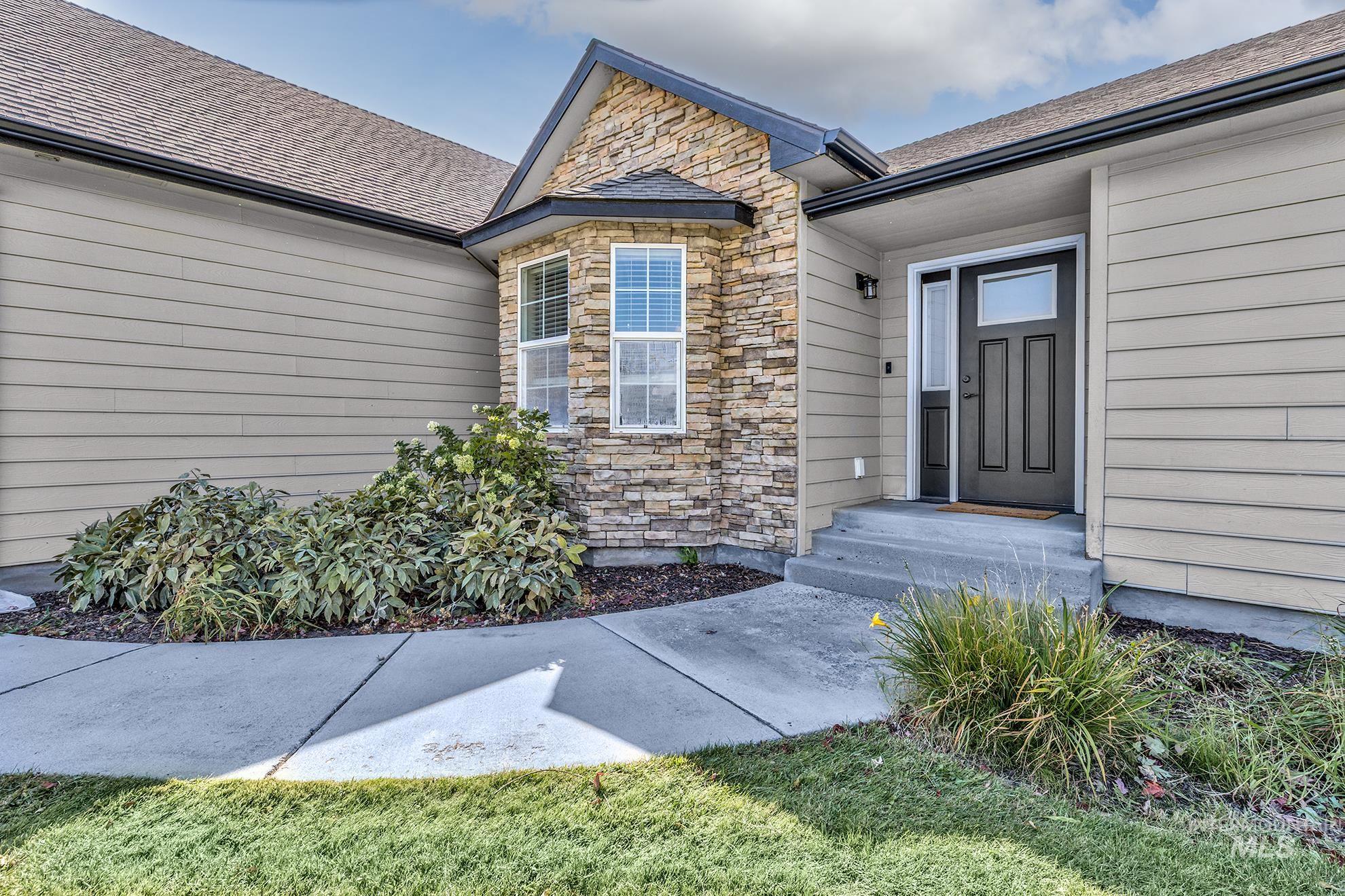 Doorway to property featuring stone siding and a shingled roof