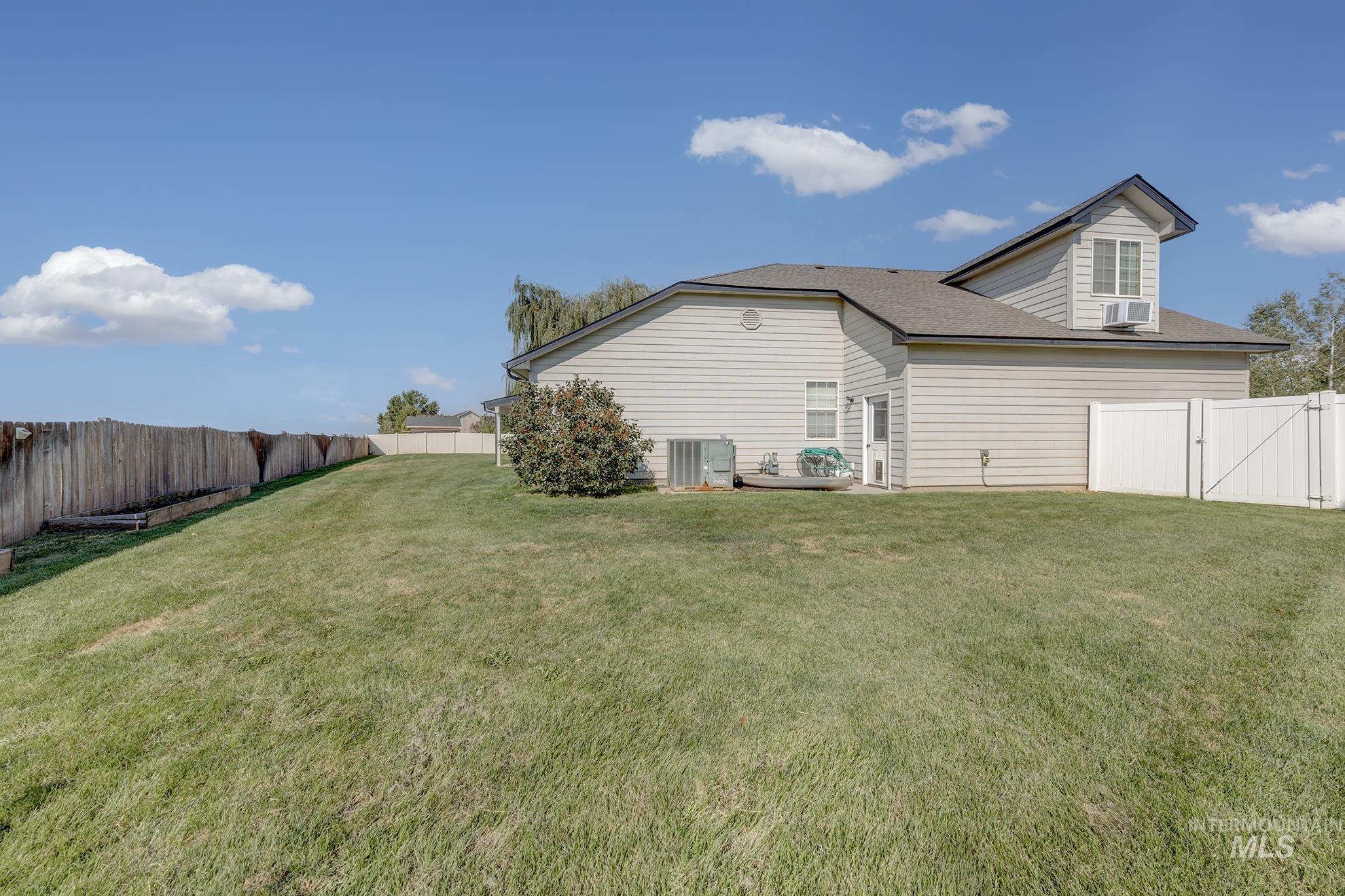 Rear view of property featuring a fenced backyard, a gate, and a shingled roof