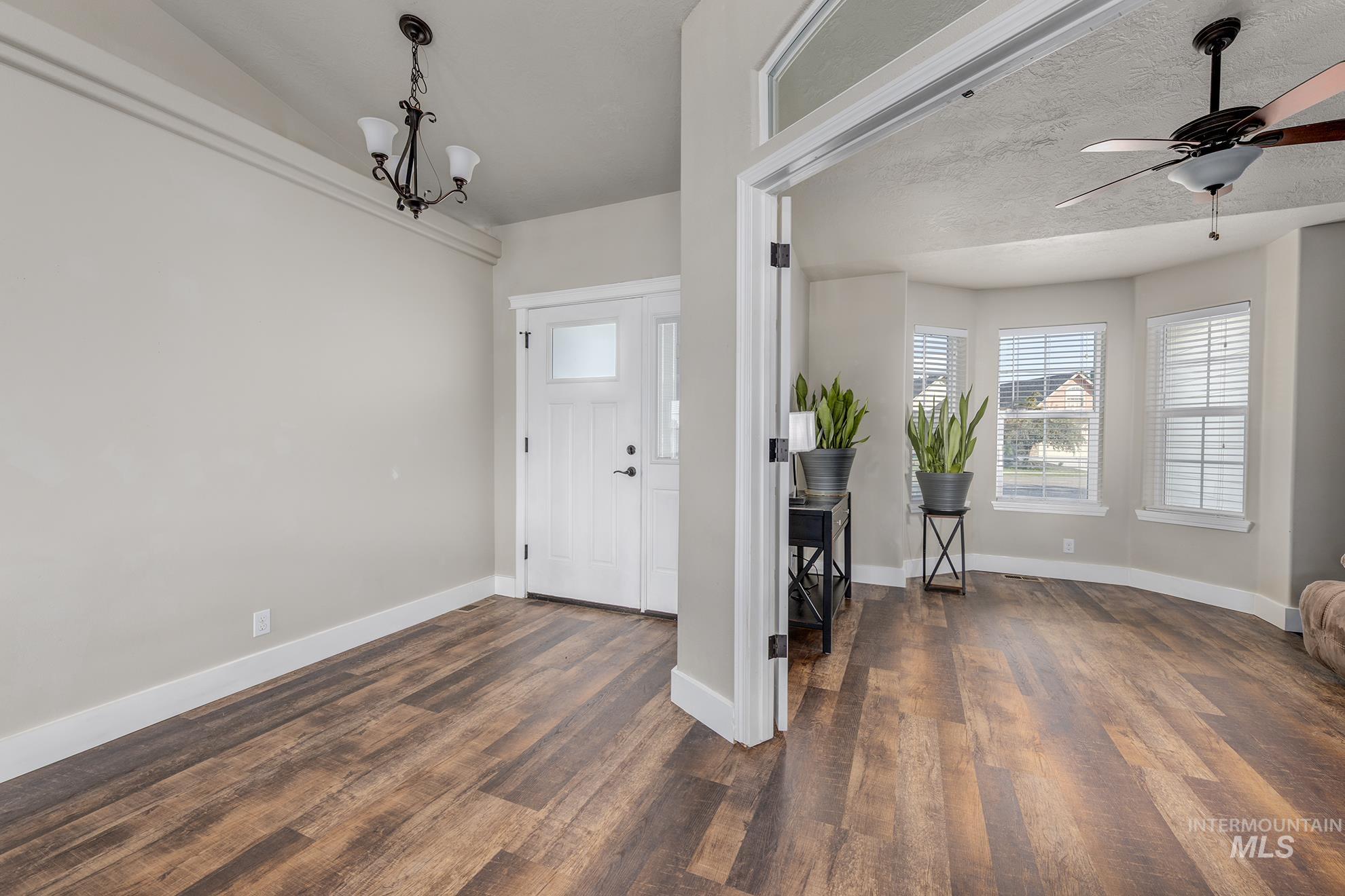 Entryway featuring dark wood-style floors, a ceiling fan, a chandelier, and a textured ceiling