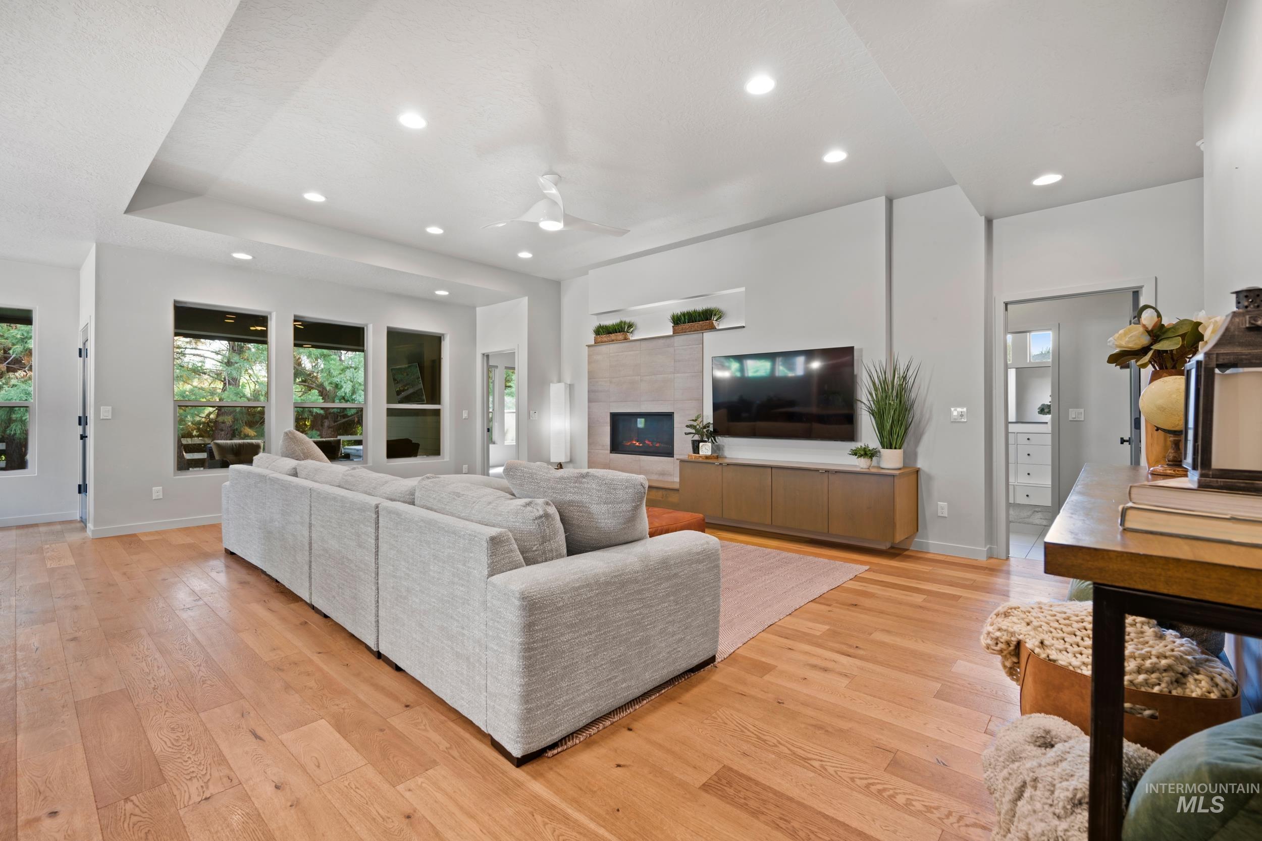 Living area with ceiling fan, recessed lighting, light wood-style flooring, and a tile fireplace