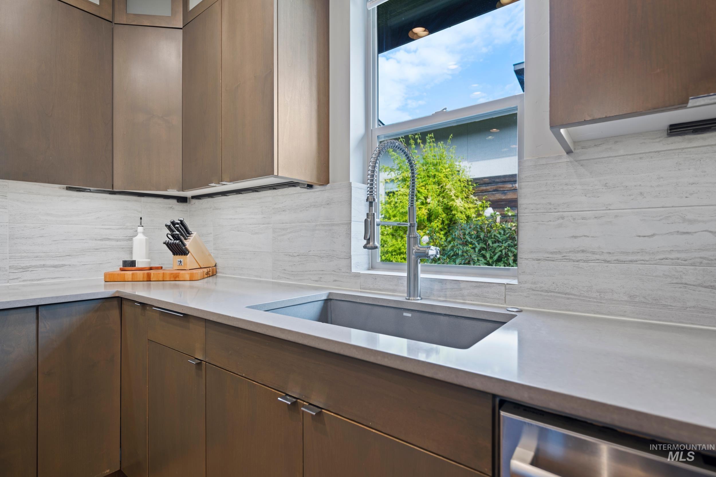 Kitchen with healthy amount of natural light, tasteful backsplash, dishwasher, and light stone counters