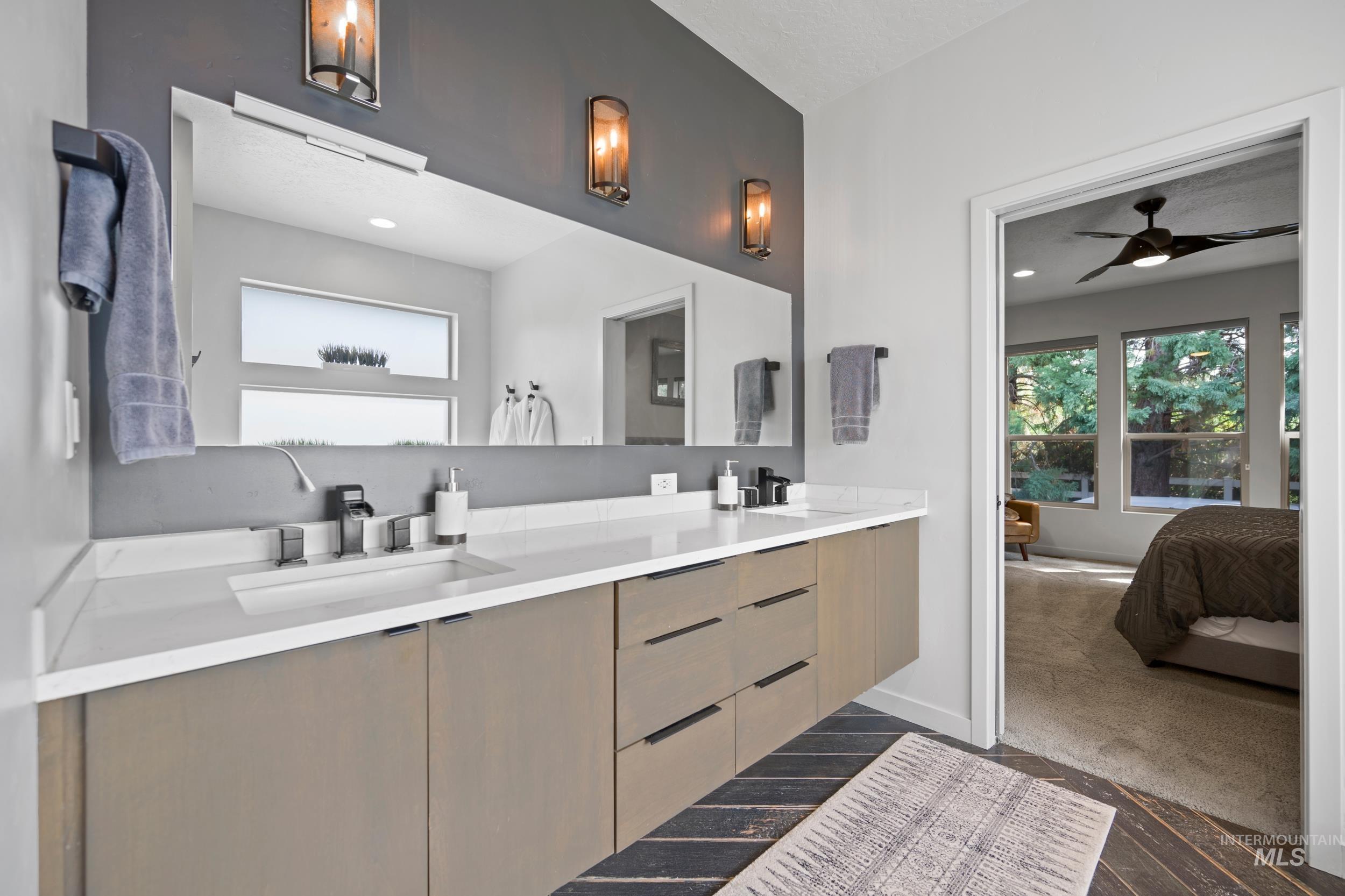 Full bathroom with double vanity, ensuite bath, and ceiling fan