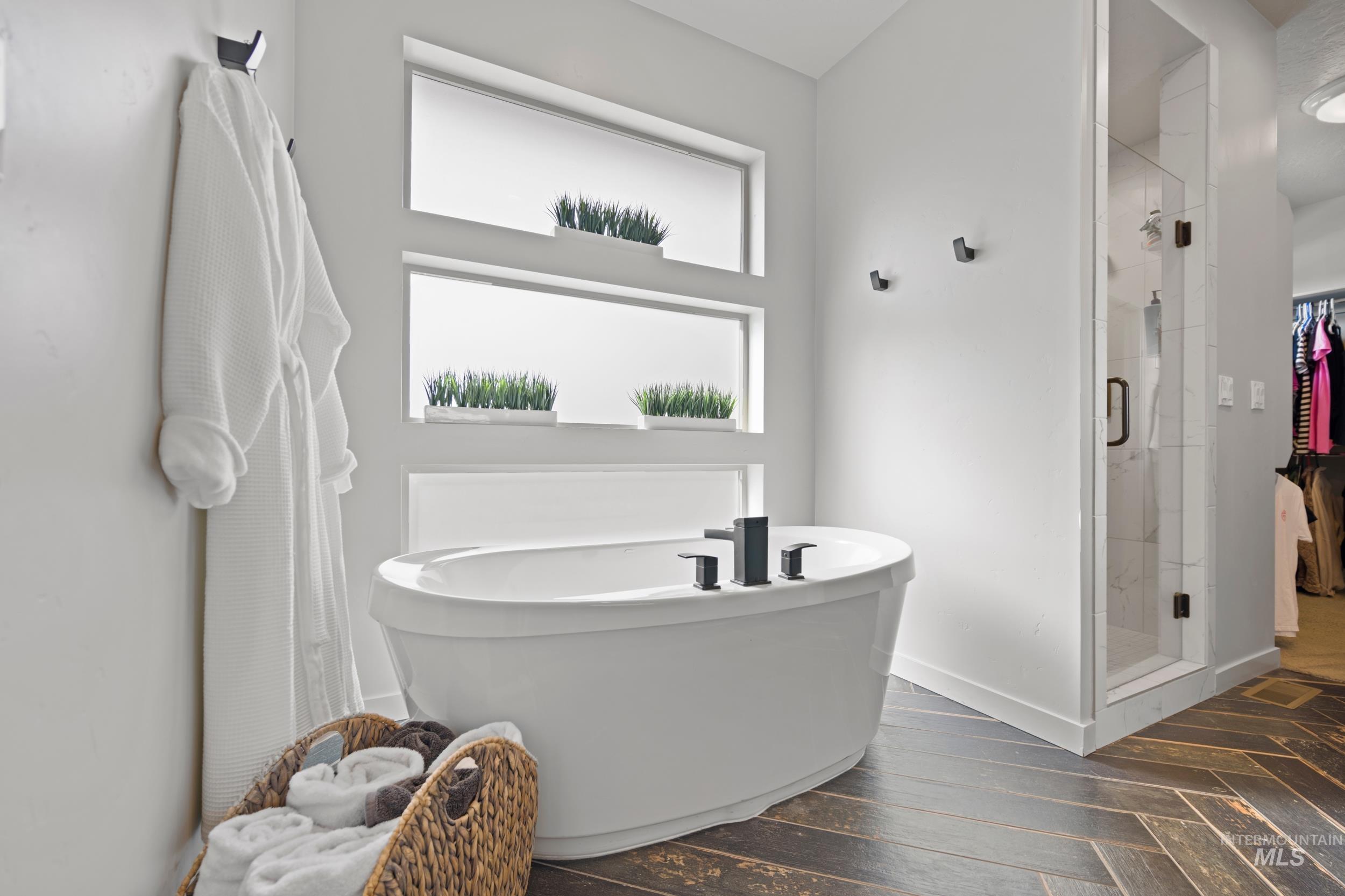 Bathroom with a soaking tub, a shower stall, and dark wood-type flooring