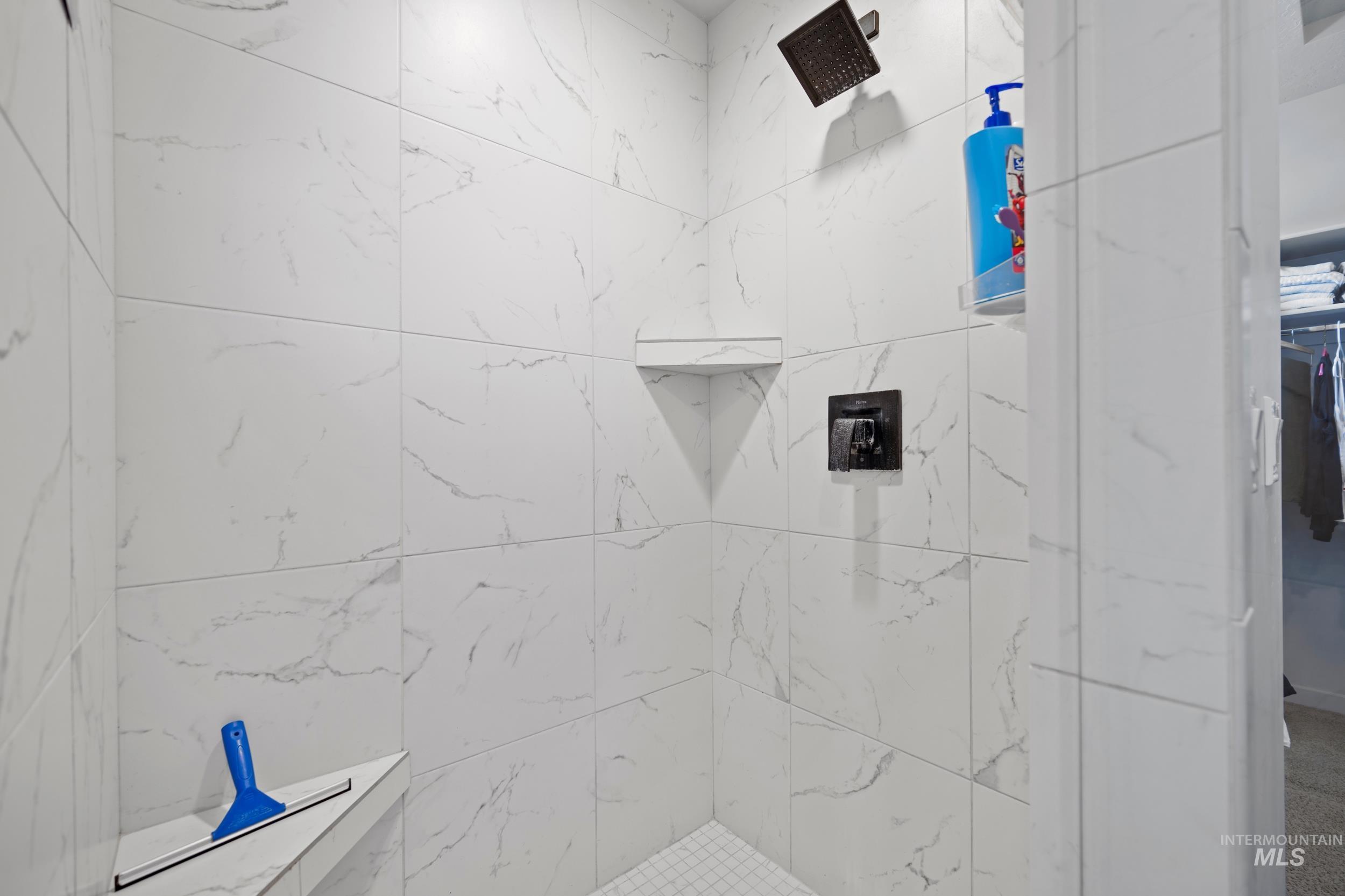 Bathroom featuring tiled shower and a spacious closet