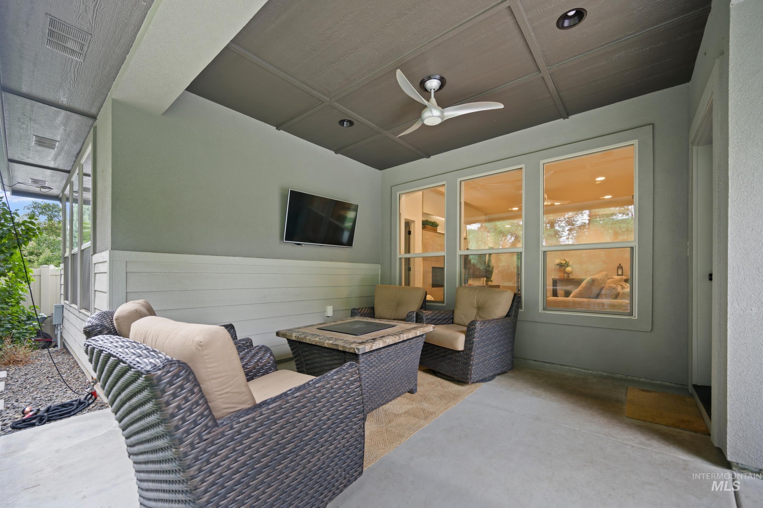 View of patio with ceiling fan and an outdoor living space with a fire pit