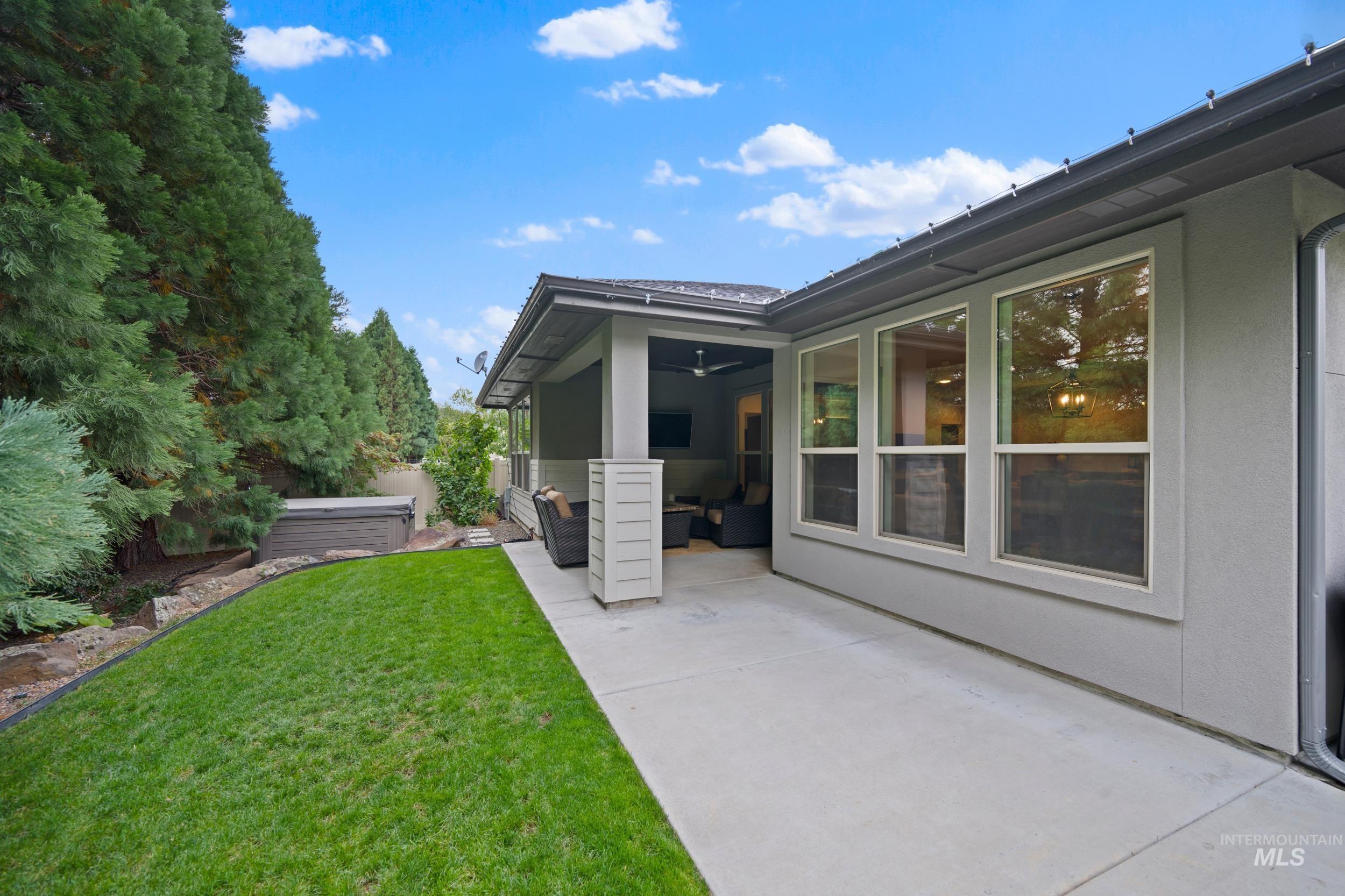View of grassy yard with a hot tub, a patio, and a sunroom