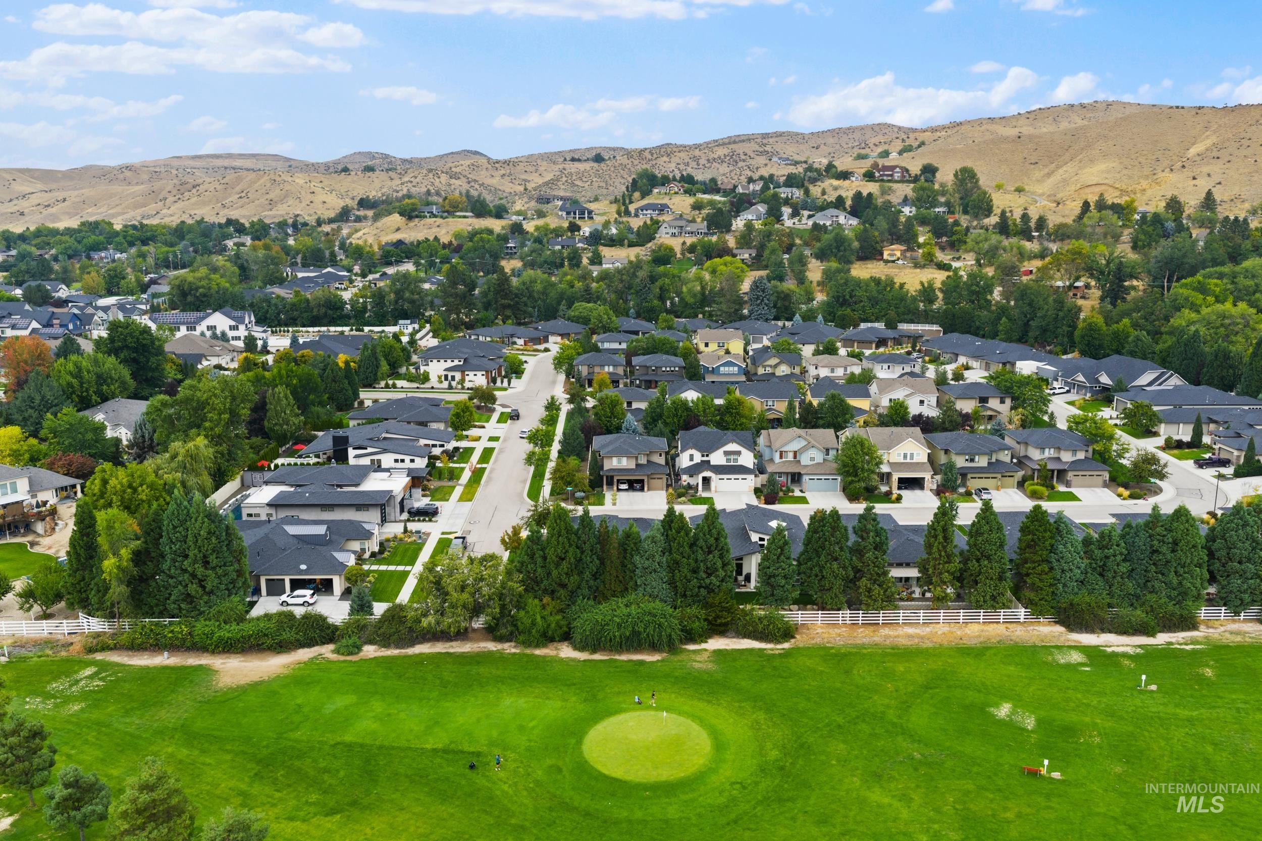 Aerial view of residential area featuring a mountainous background and a golf course