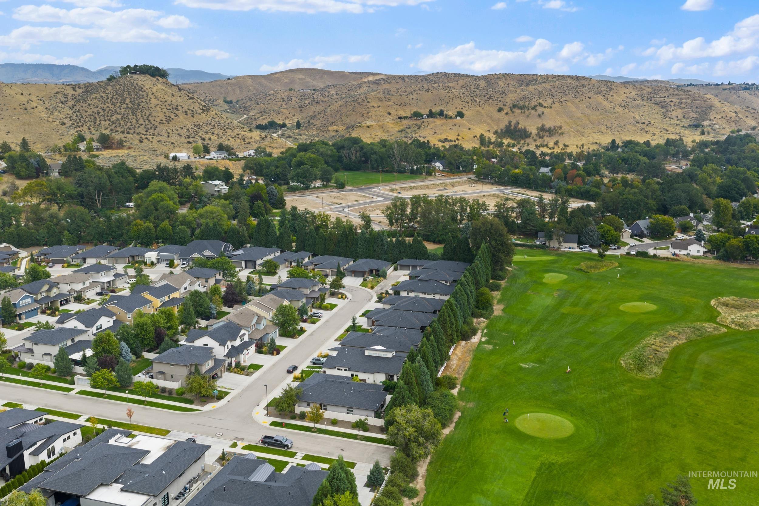 Aerial view of property and surrounding area with a mountainous background, nearby suburban area, and a golf course