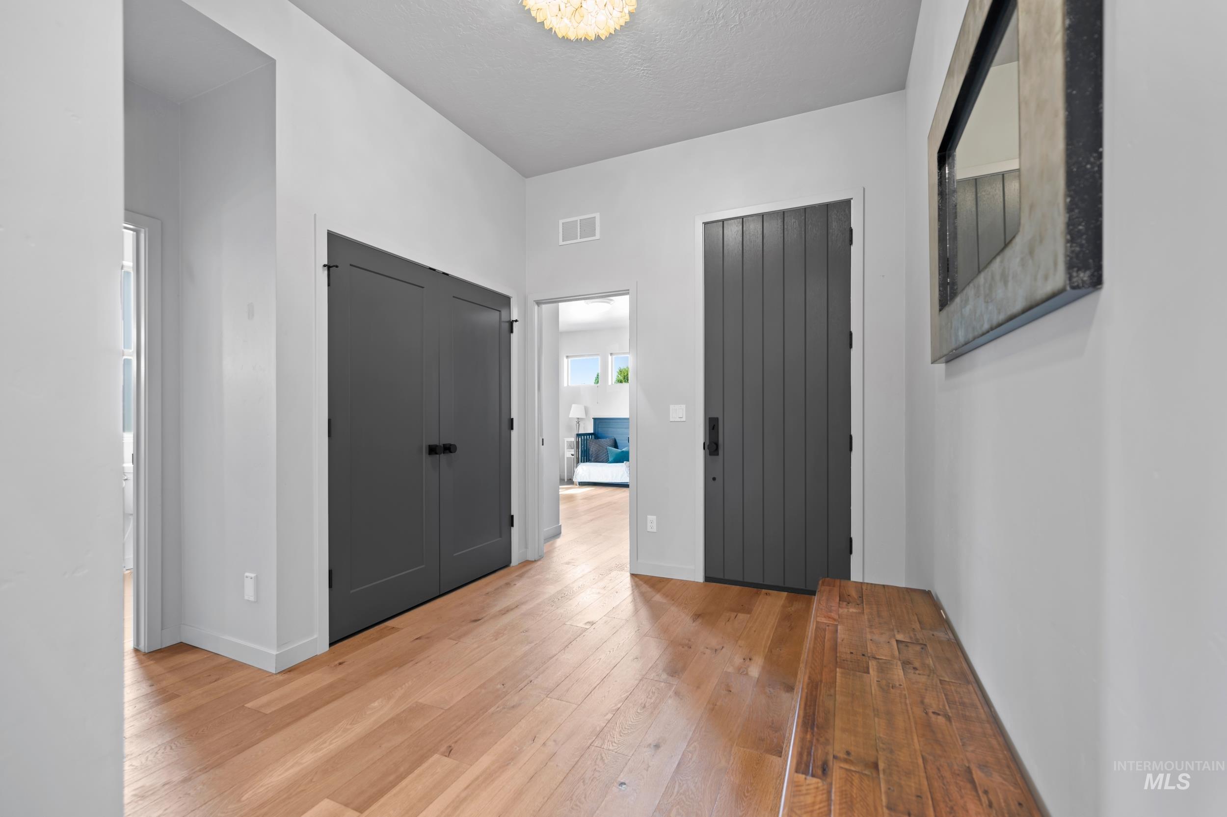 Foyer featuring light wood-style flooring, a textured ceiling, and a chandelier