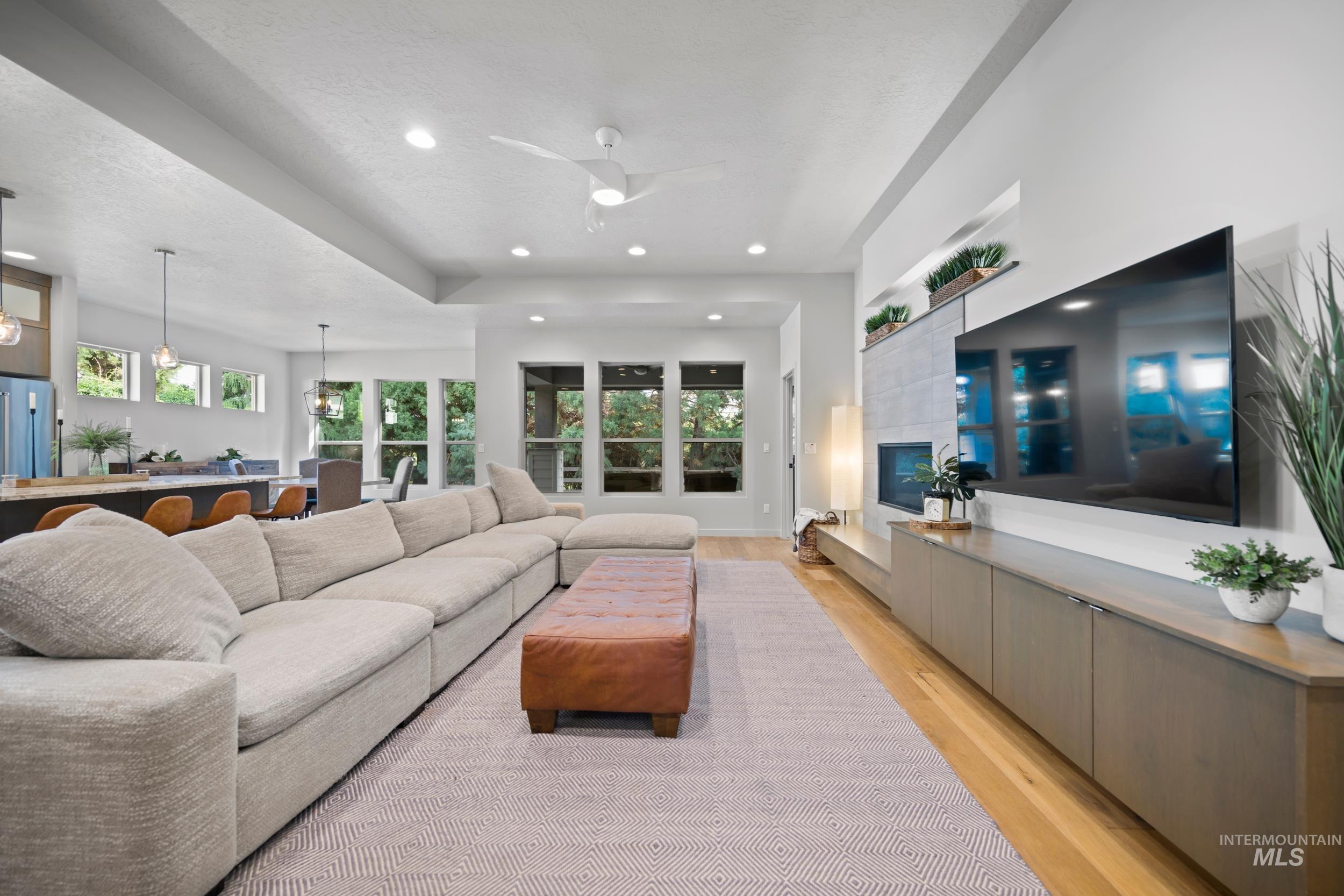 Living area with light wood finished floors, healthy amount of natural light, recessed lighting, a ceiling fan, and a textured ceiling