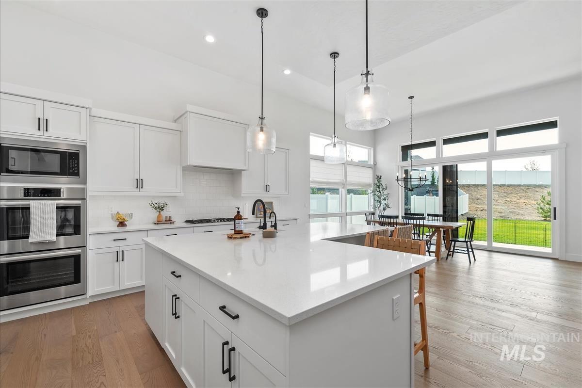 Kitchen with white cabinetry, decorative backsplash, stainless steel appliances, recessed lighting, and decorative light fixtures