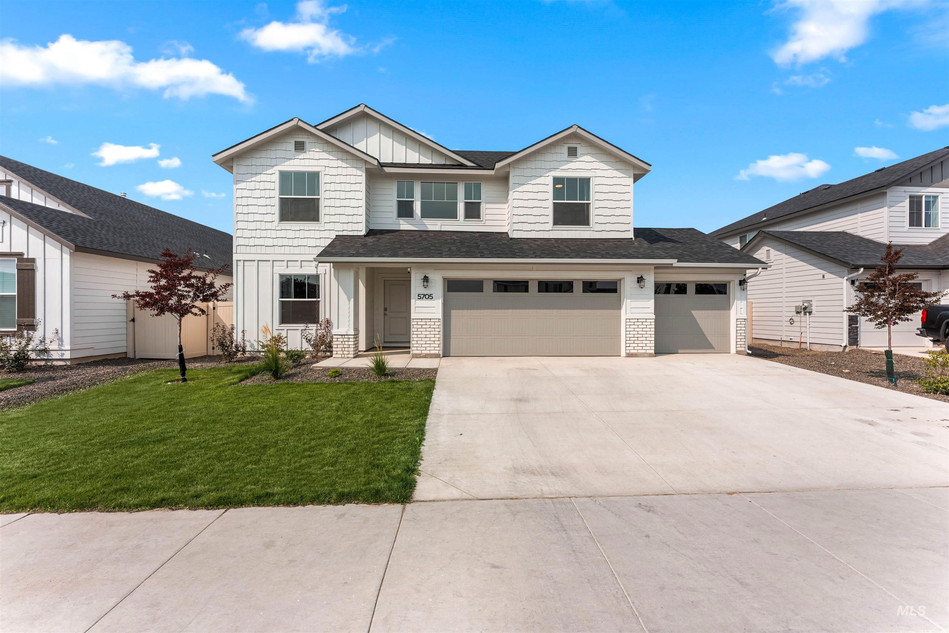 View of front facade with board and batten siding, concrete driveway, a garage, a front yard, and a shingled roof