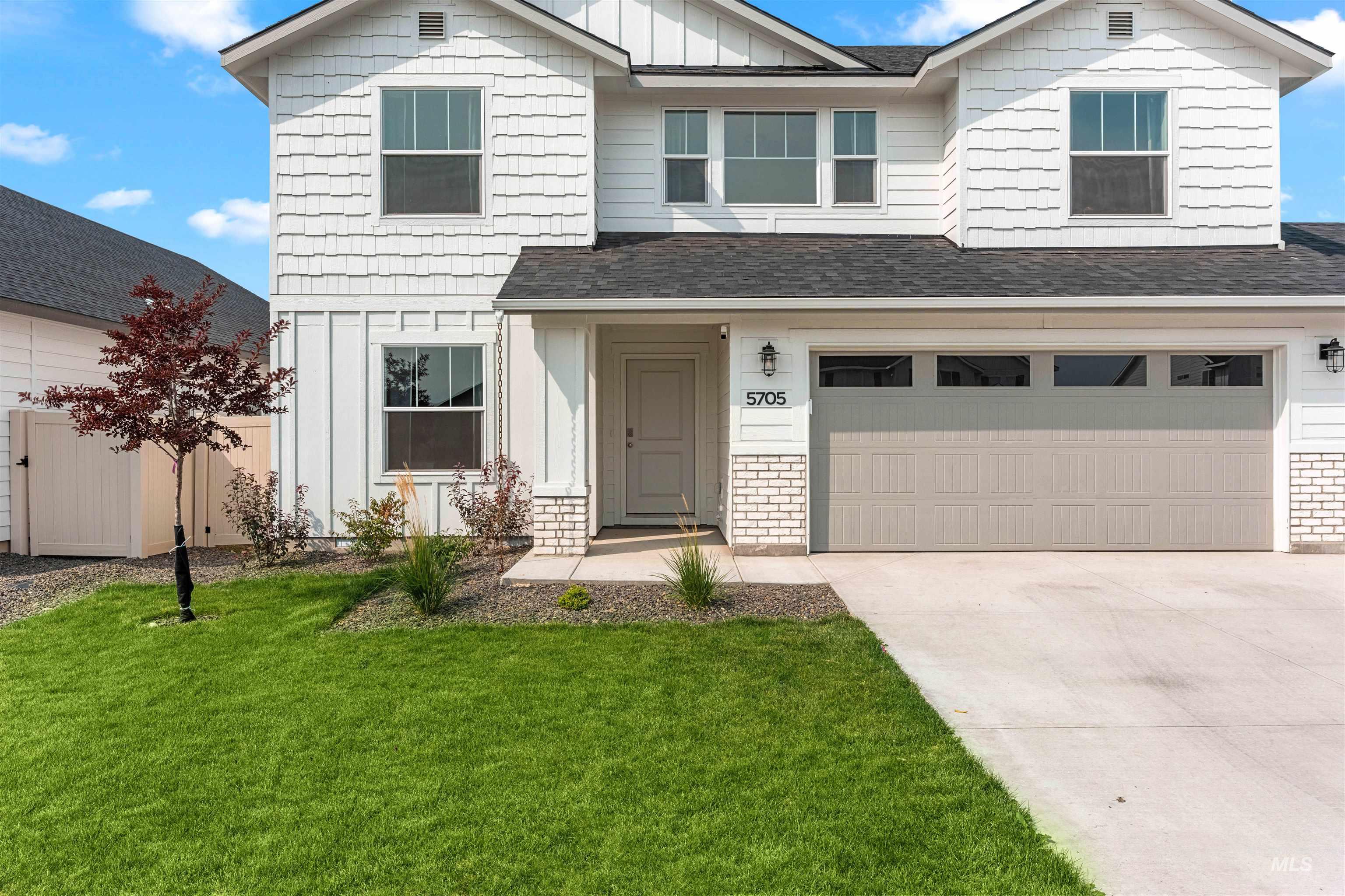 Craftsman inspired home featuring board and batten siding, driveway, roof with shingles, a front yard, and an attached garage
