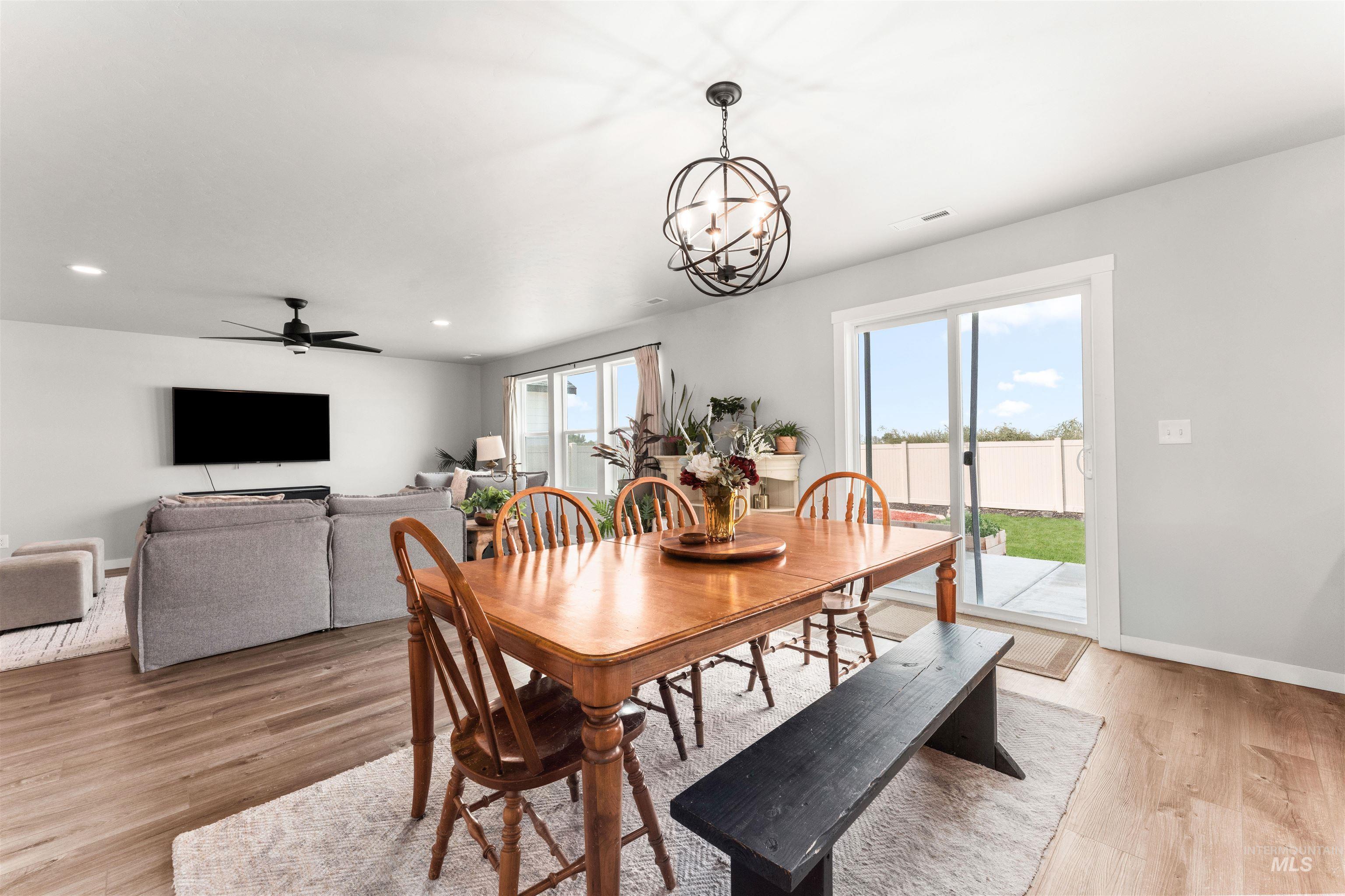 Dining room featuring light wood-style flooring, a ceiling fan, a chandelier, and recessed lighting