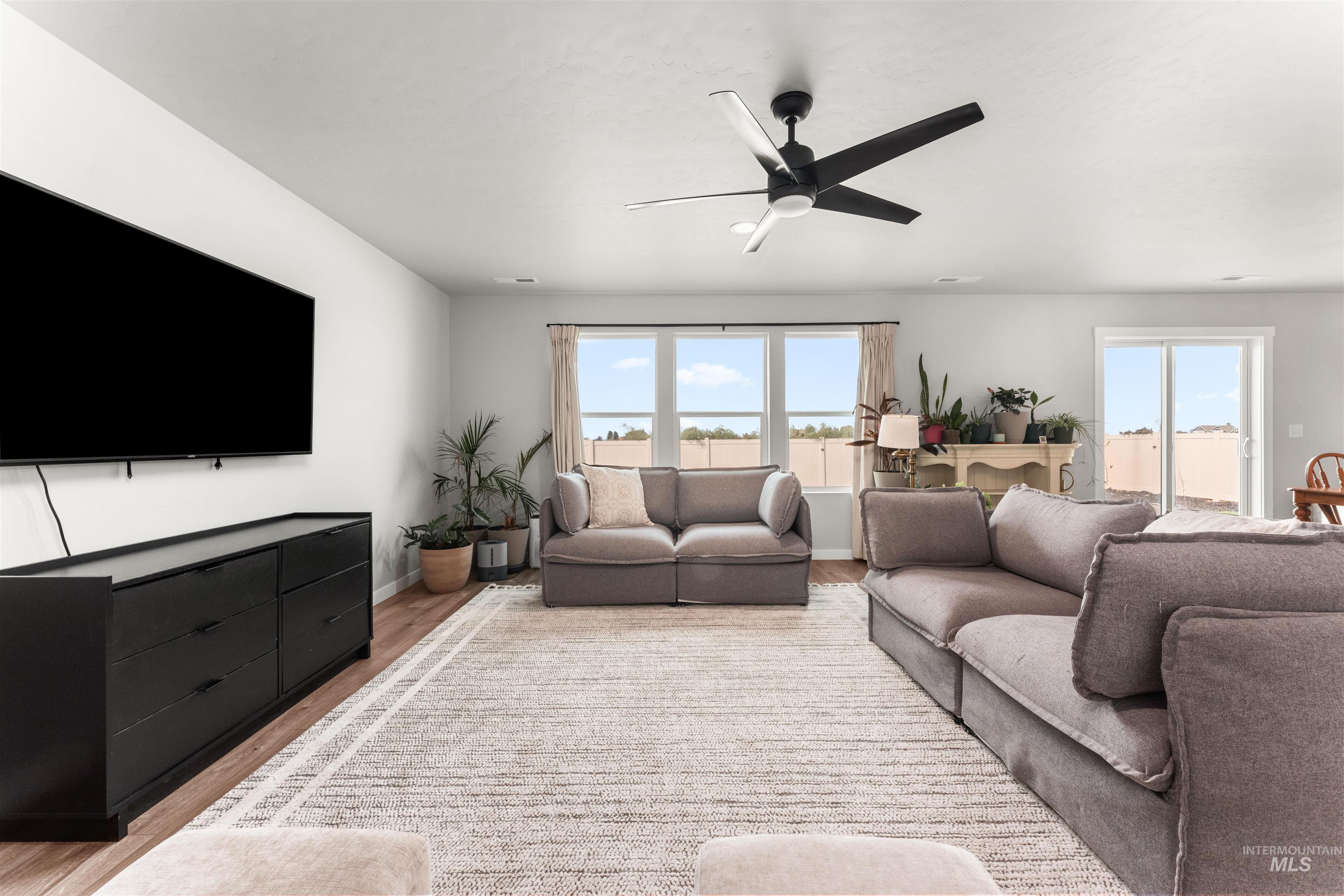 Living room with light wood-type flooring and a ceiling fan