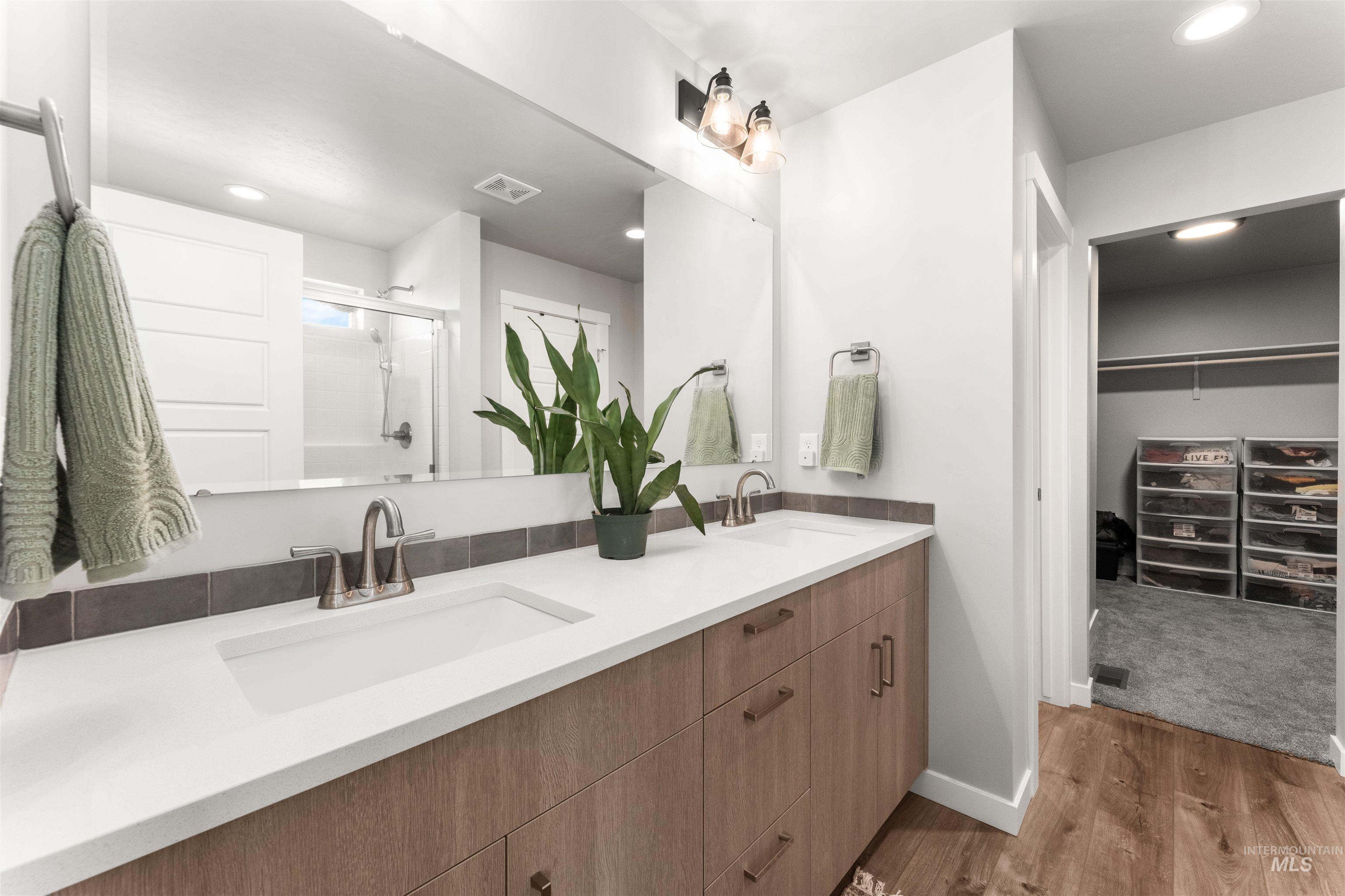 Full bathroom featuring recessed lighting, double vanity, a shower stall, light wood-style flooring, and a walk in closet