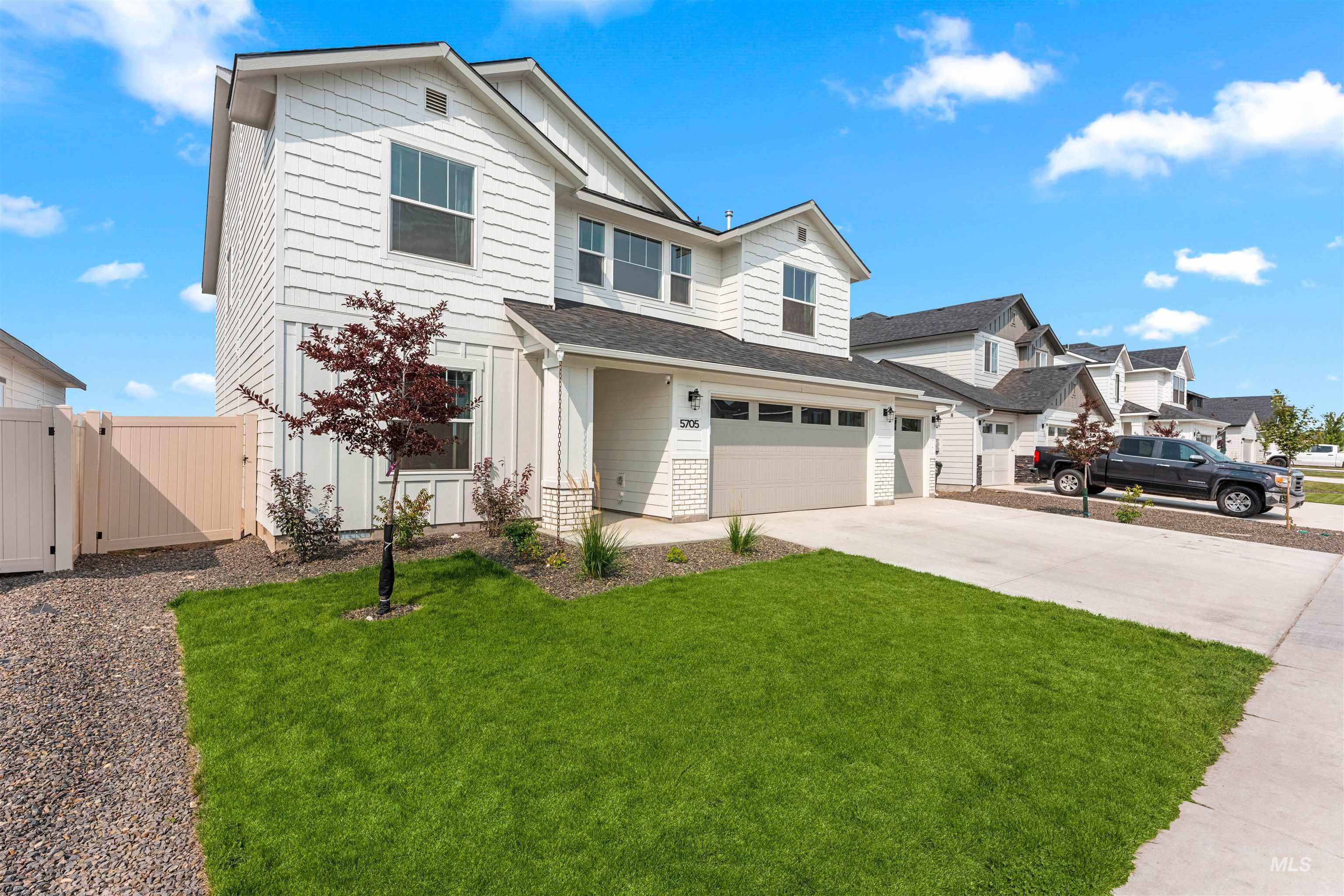 View of front of property featuring board and batten siding, driveway, an attached garage, a gate, and a residential view