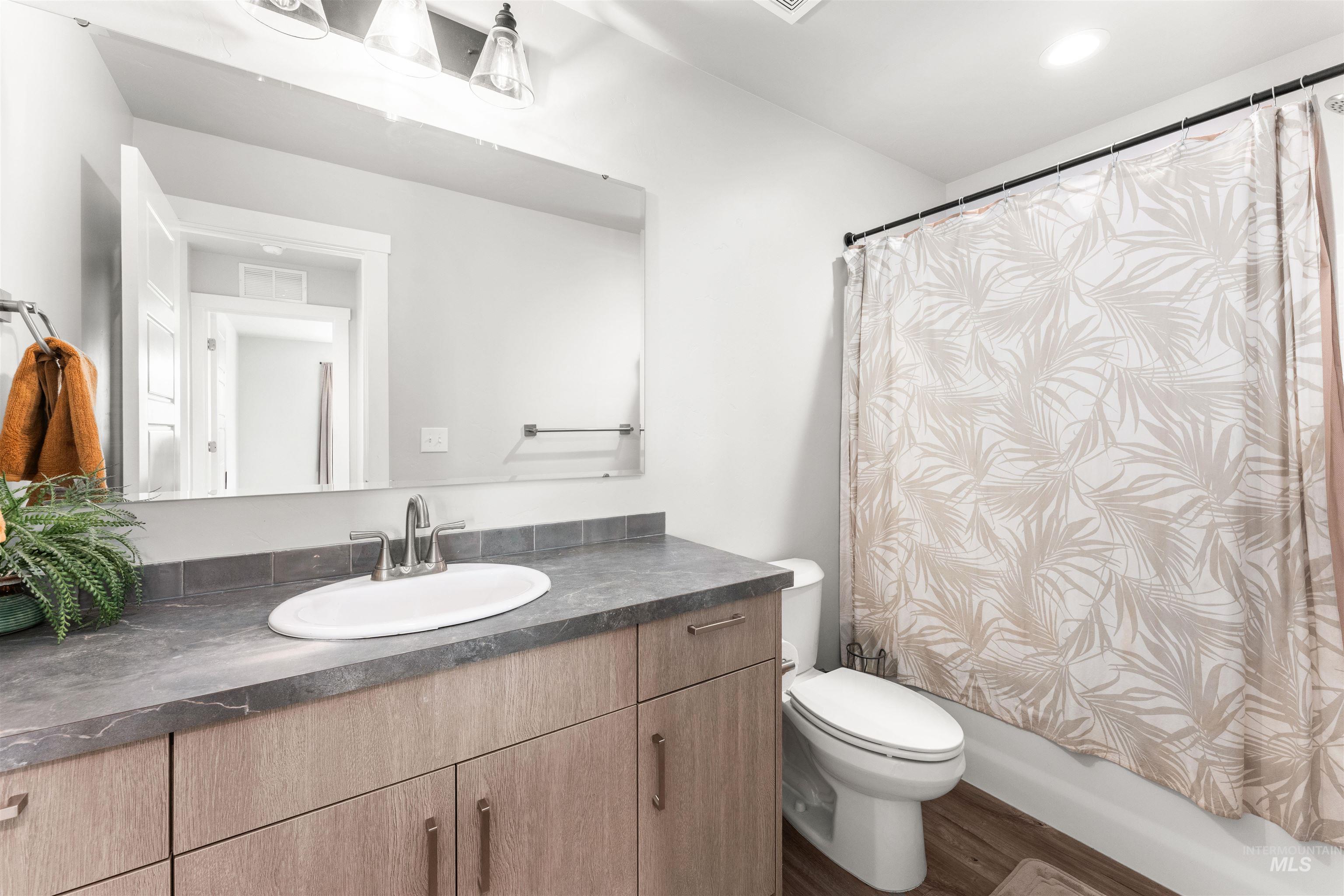 Bathroom with vanity, dark wood-style flooring, and shower / tub combo