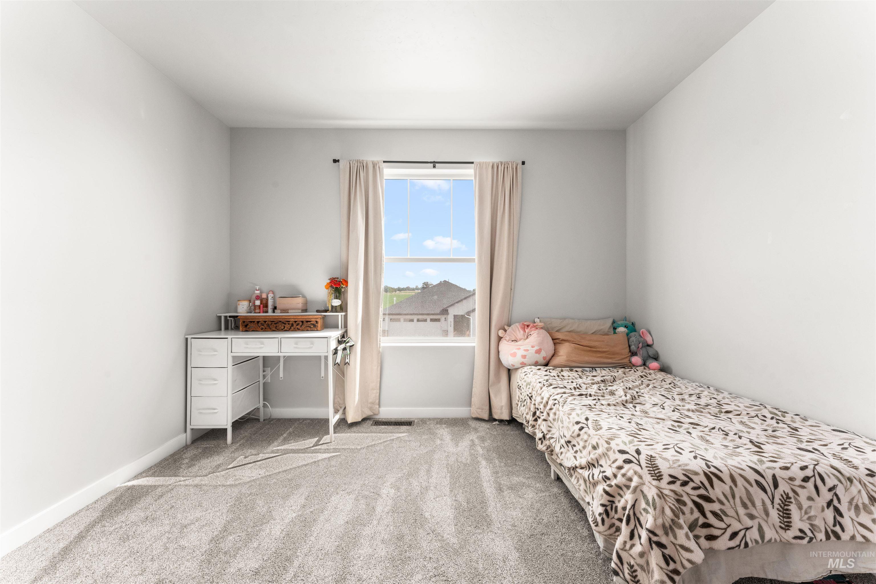 Bedroom featuring light carpet and baseboards