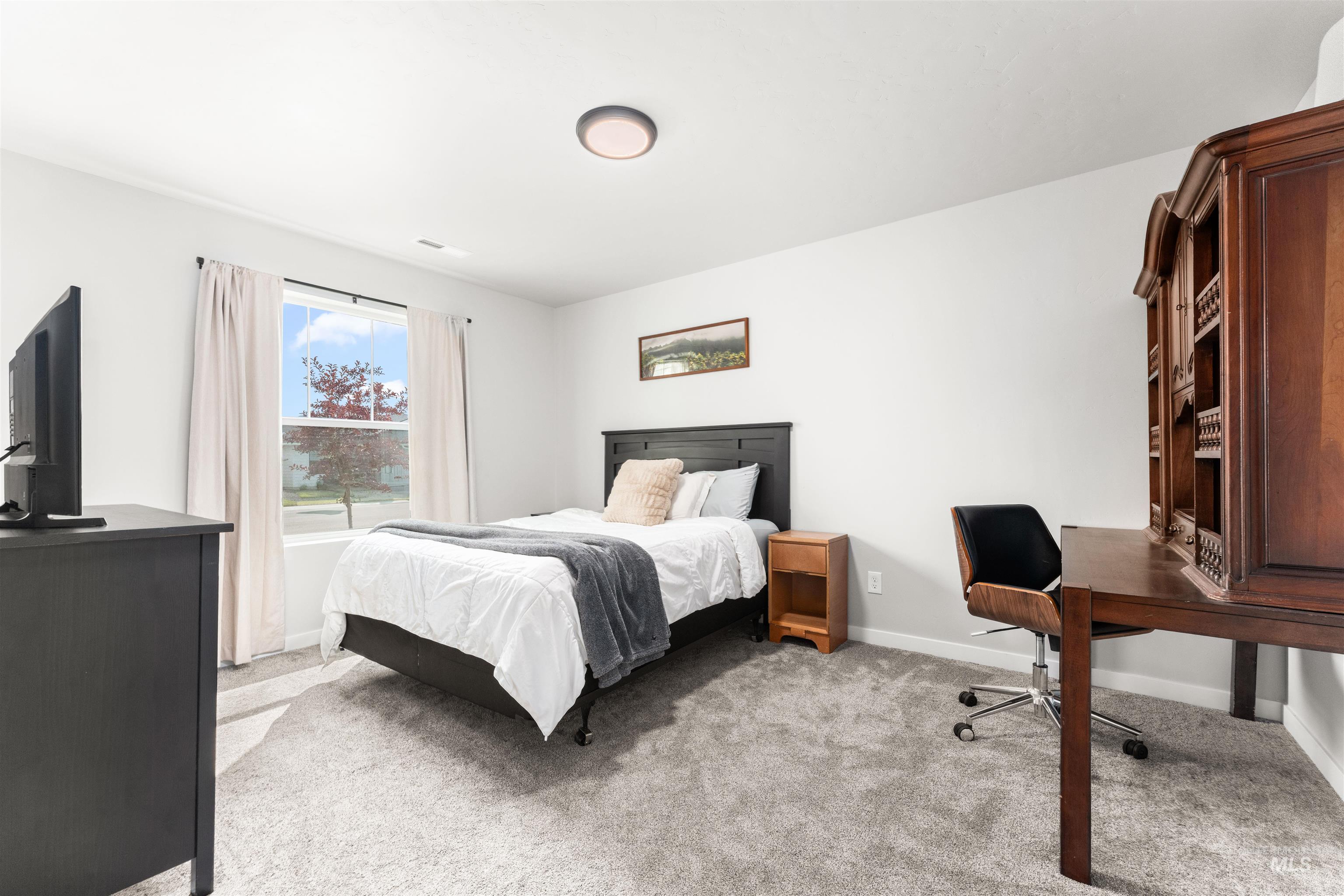 Bedroom with light carpet and a desk