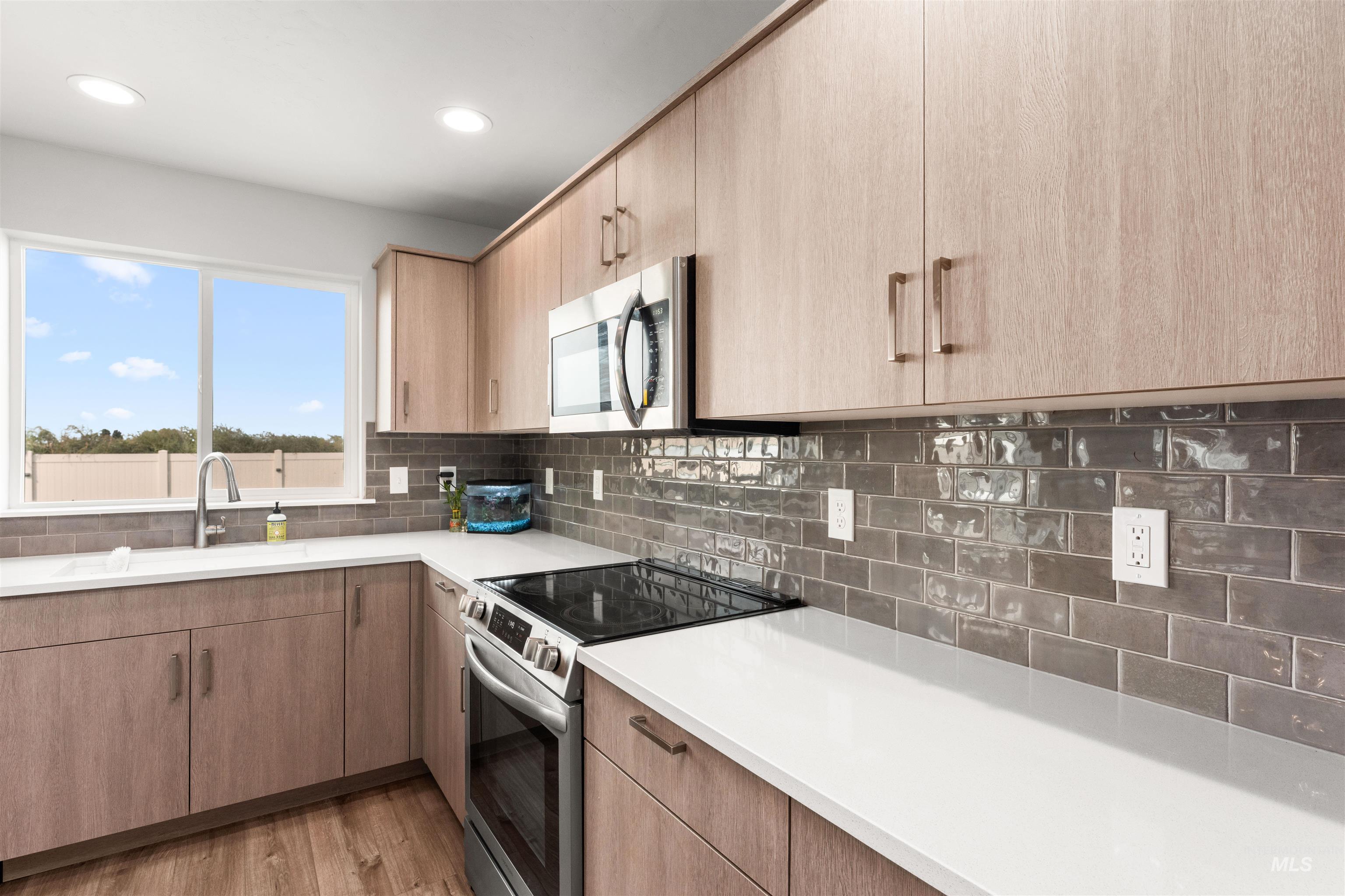Kitchen featuring stainless steel appliances, backsplash, light wood finished floors, recessed lighting, and light brown cabinets