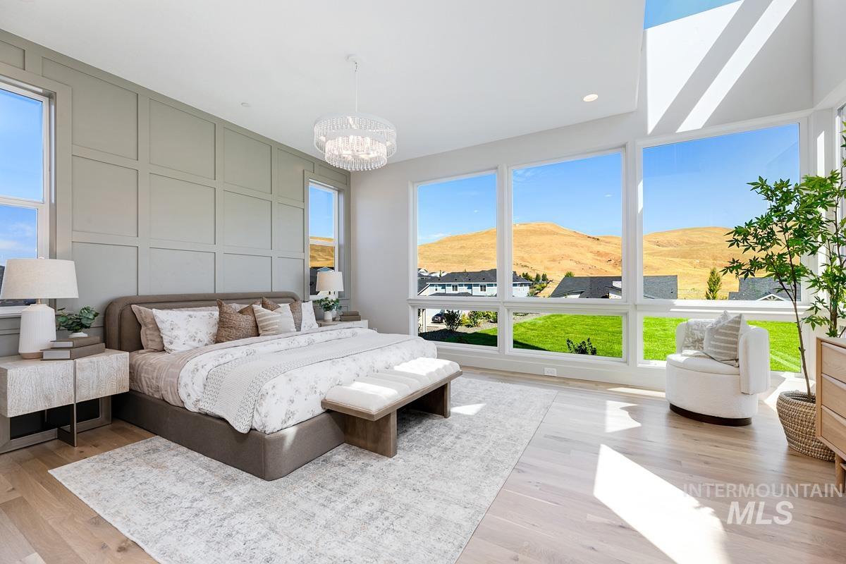 Bedroom featuring a decorative wall, light wood-style flooring, a mountain view, a chandelier, and recessed lighting