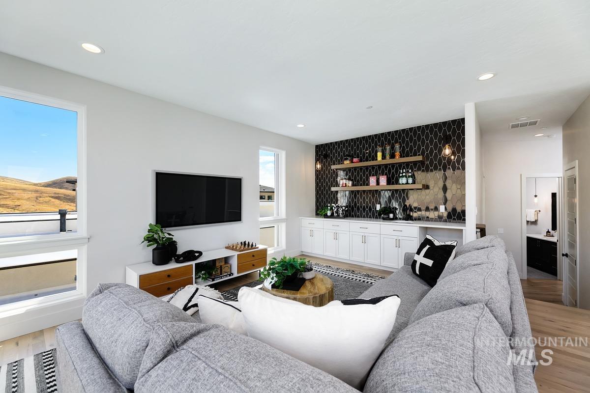 Living area featuring light wood-type flooring, a bar, and recessed lighting