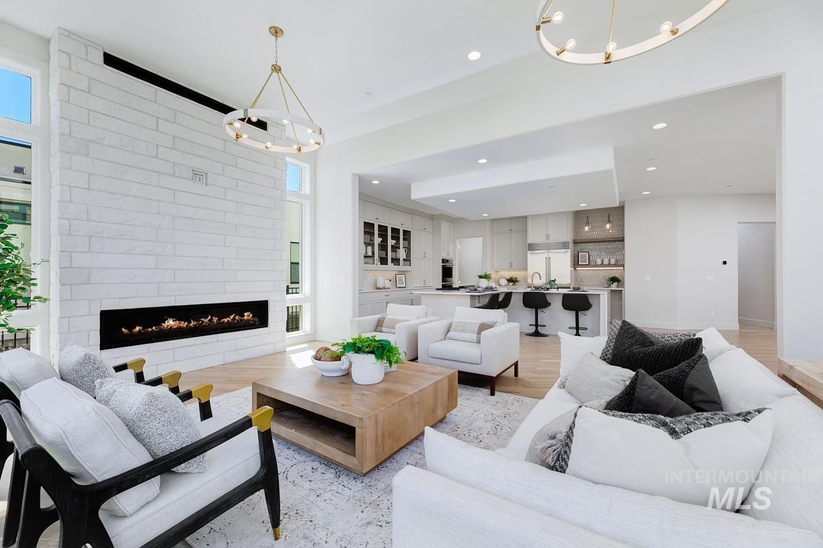 Living area with a chandelier, light wood-type flooring, a large fireplace, and recessed lighting